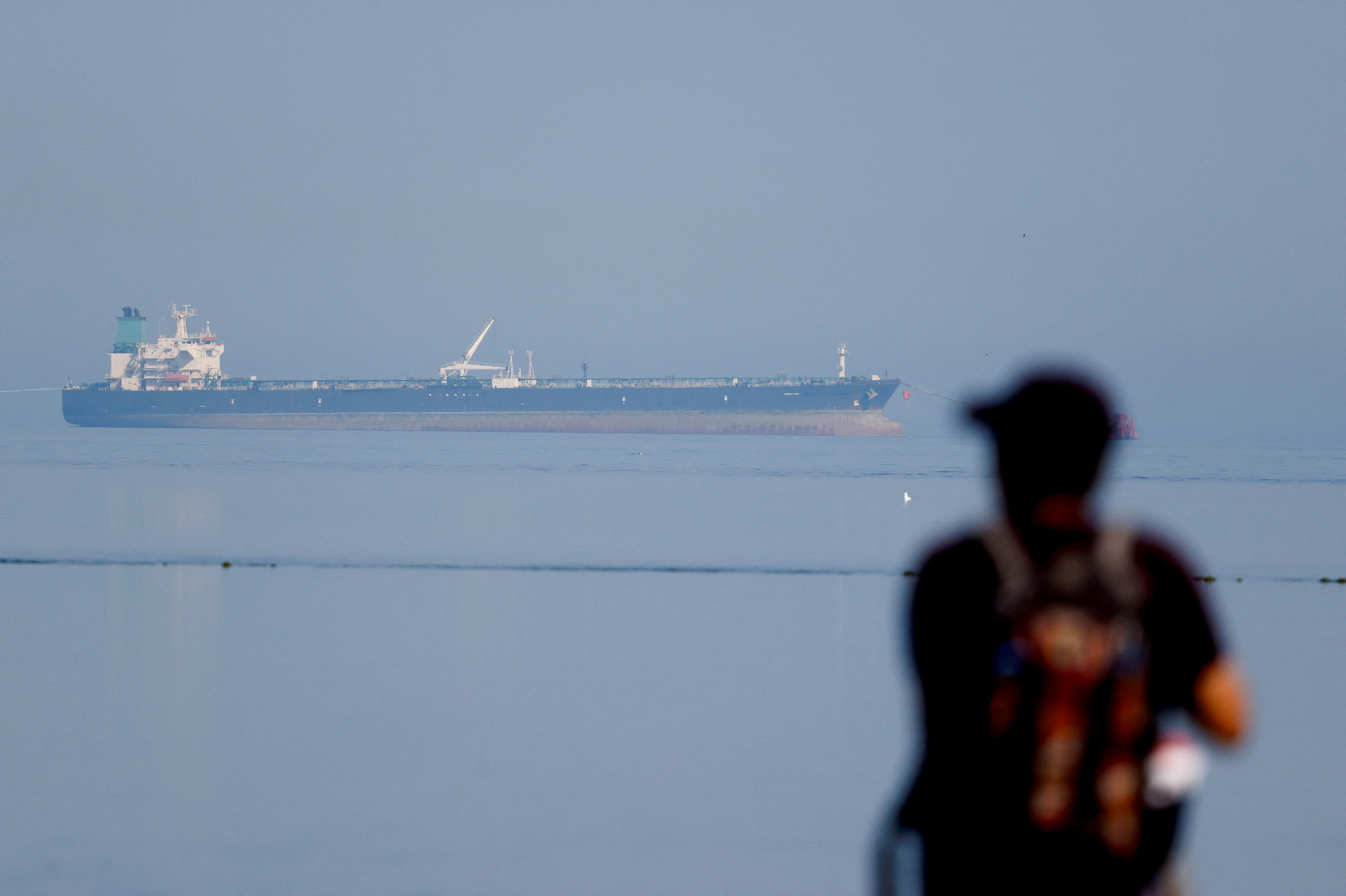 FILE PHOTO: A tourist watches the MT Desert Kite oil tanker carrying Russian oil at Narara Marine National Park in the Arabian Sea, Gujarat, India, March 11 , 2026.