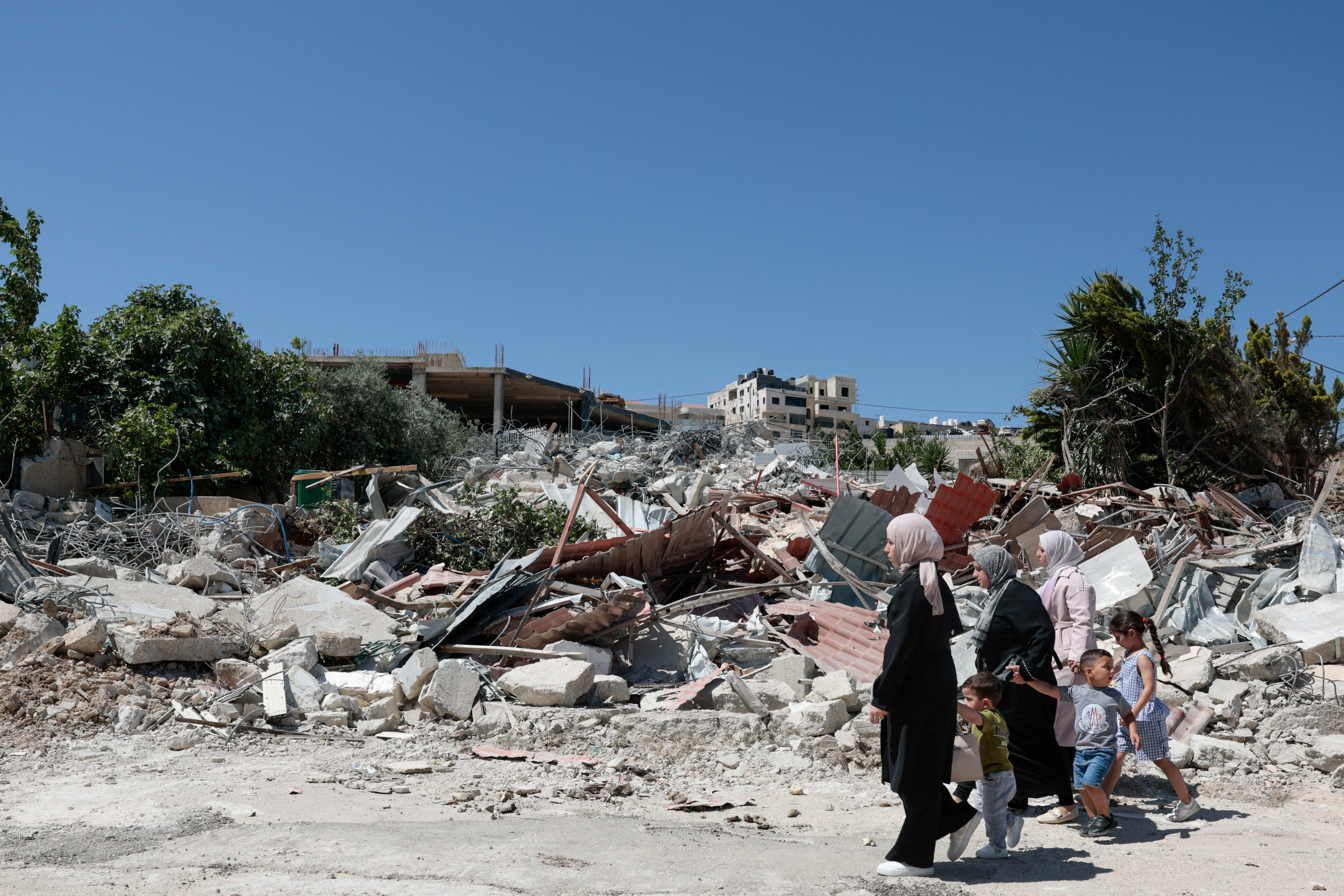 People walk past the rubble of a Palestinian building demolished by Israeli military in the town of Jabaa in the Israeli-occupied West Bank, near Jerusalem