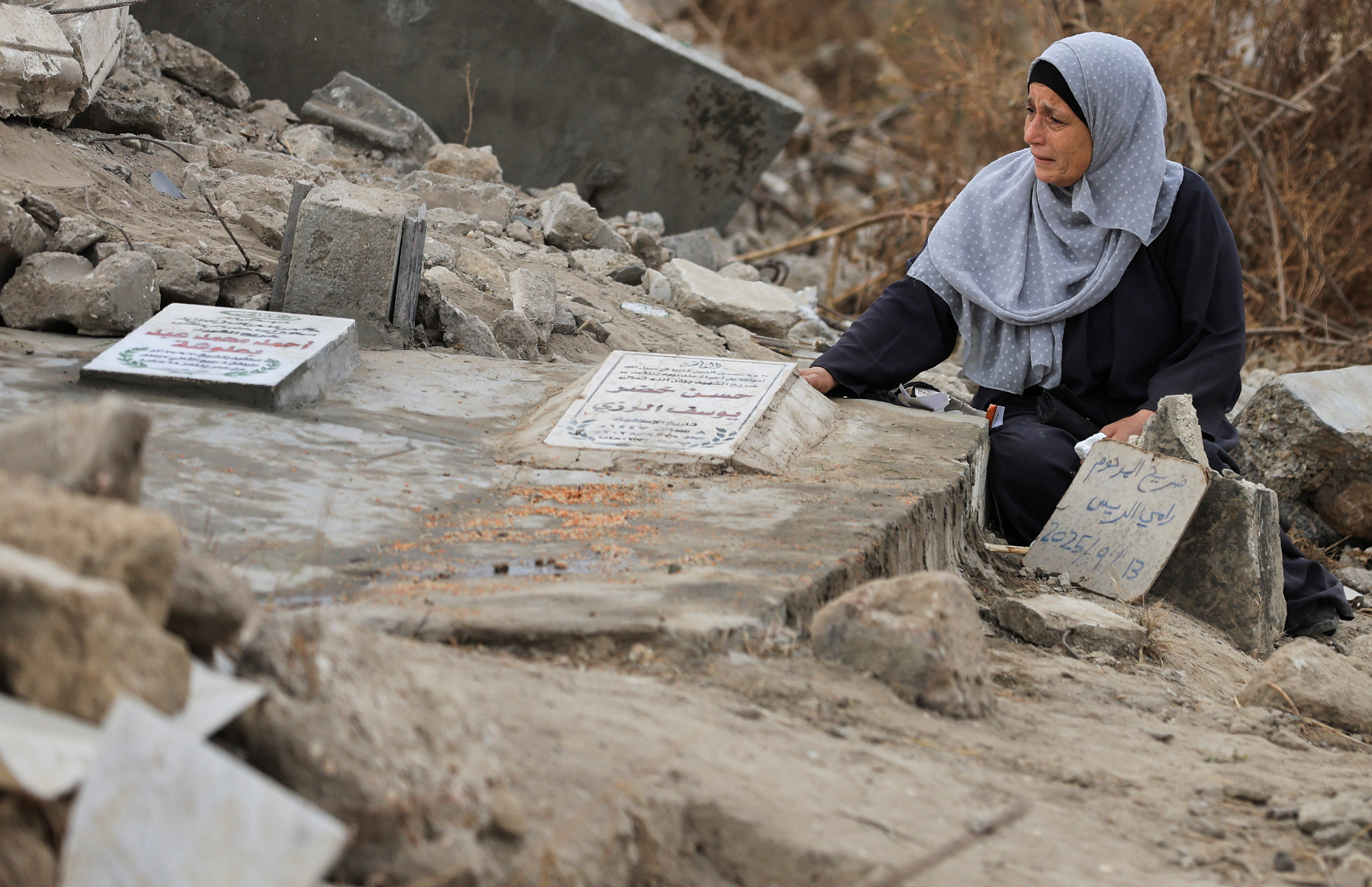 A Palestinian woman reacts as she visits a grave at a cemetery on Eid al-Adha, in Gaza City, May 27, 2026.