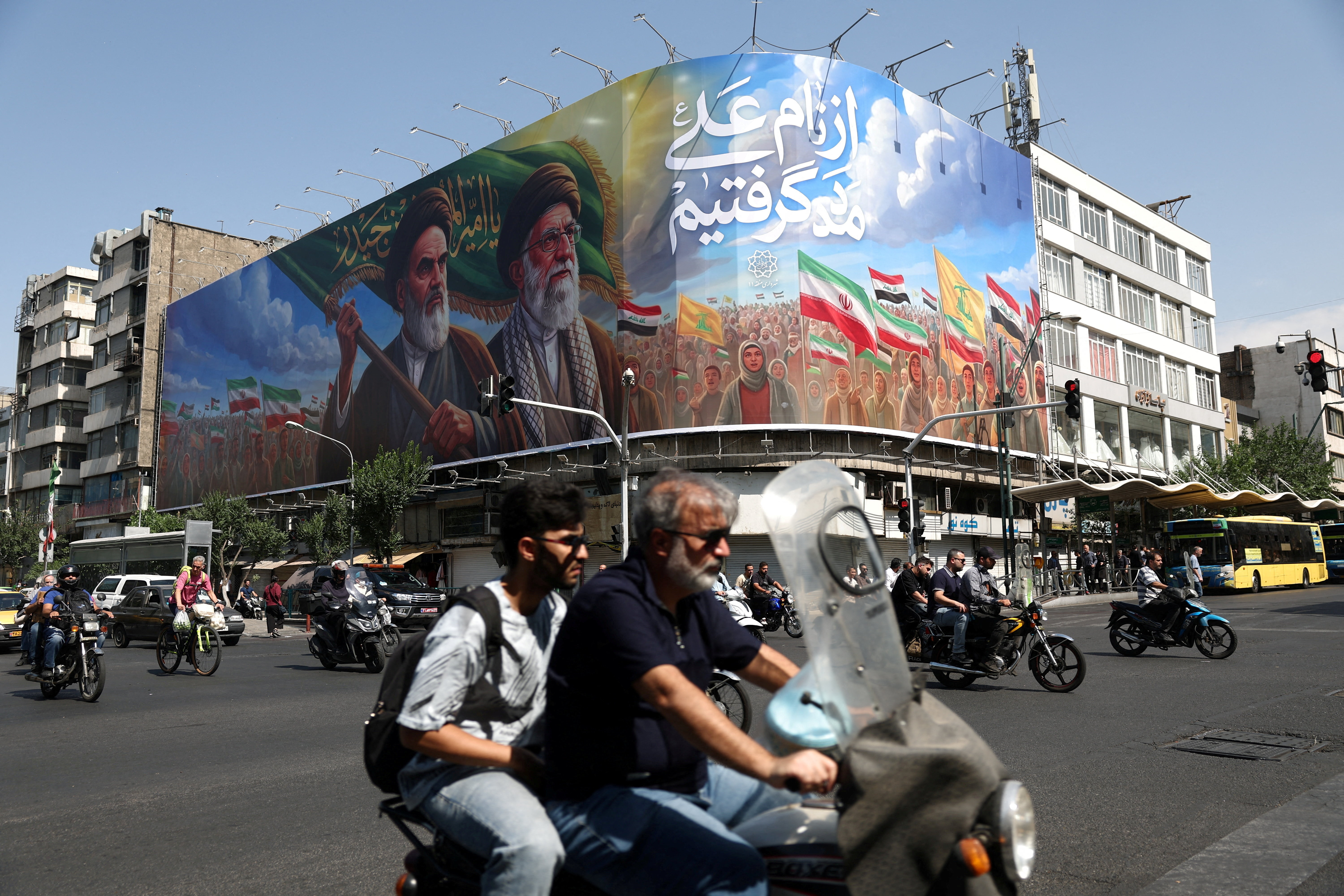 People ride past a billboard depicting the late leader of the Islamic Revolution, Ayatollah Ruhollah Khomeini, and the late Iran's Supreme Leader Ayatollah Ali Khamenei, on a street in Tehran, Iran, June 10, 2026.