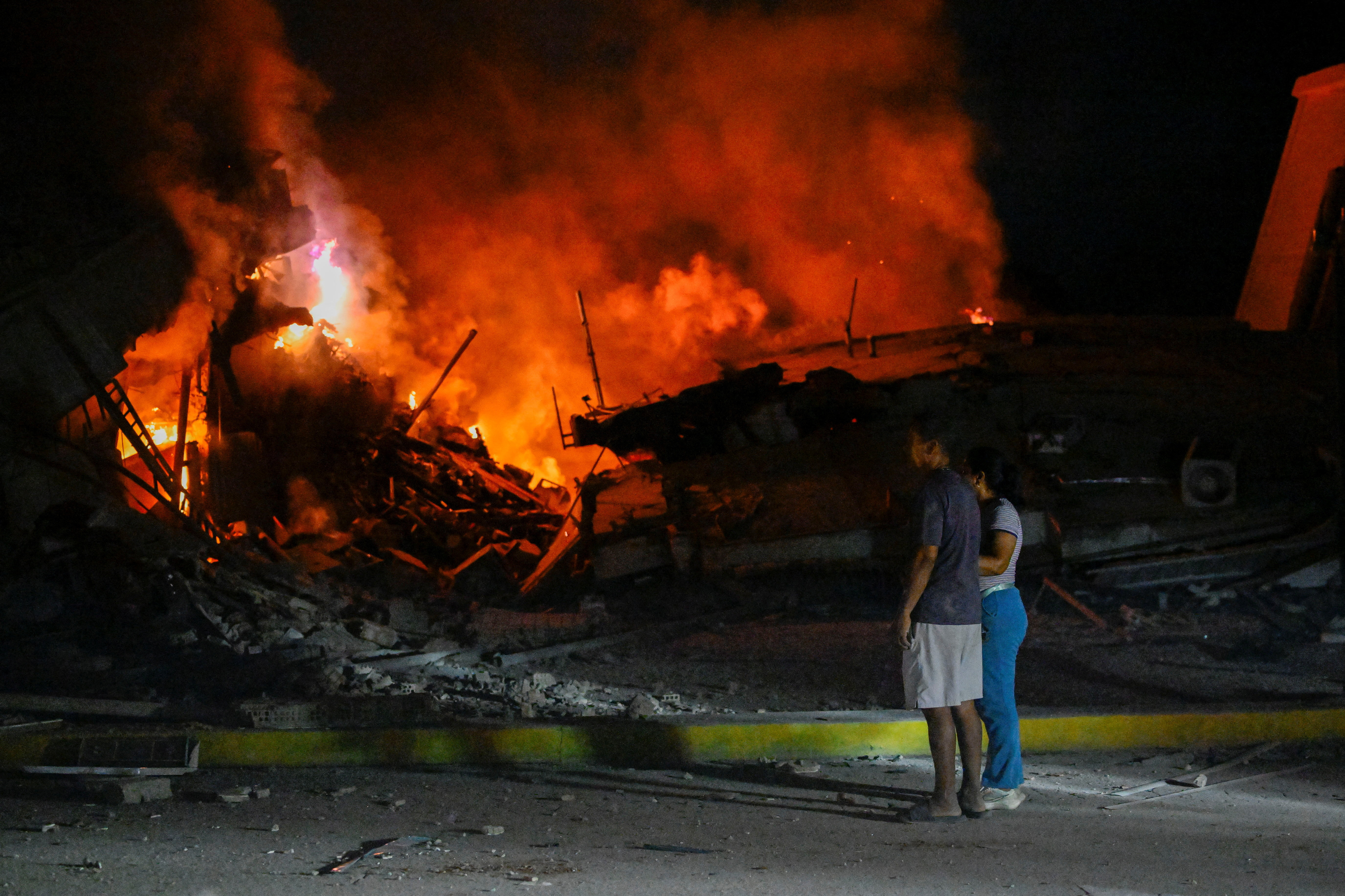 People stand near destroyed buildings after an earthquake, in La Guaira, Venezuela, June 25, 2026. REUTERS/Maxwell Briceno