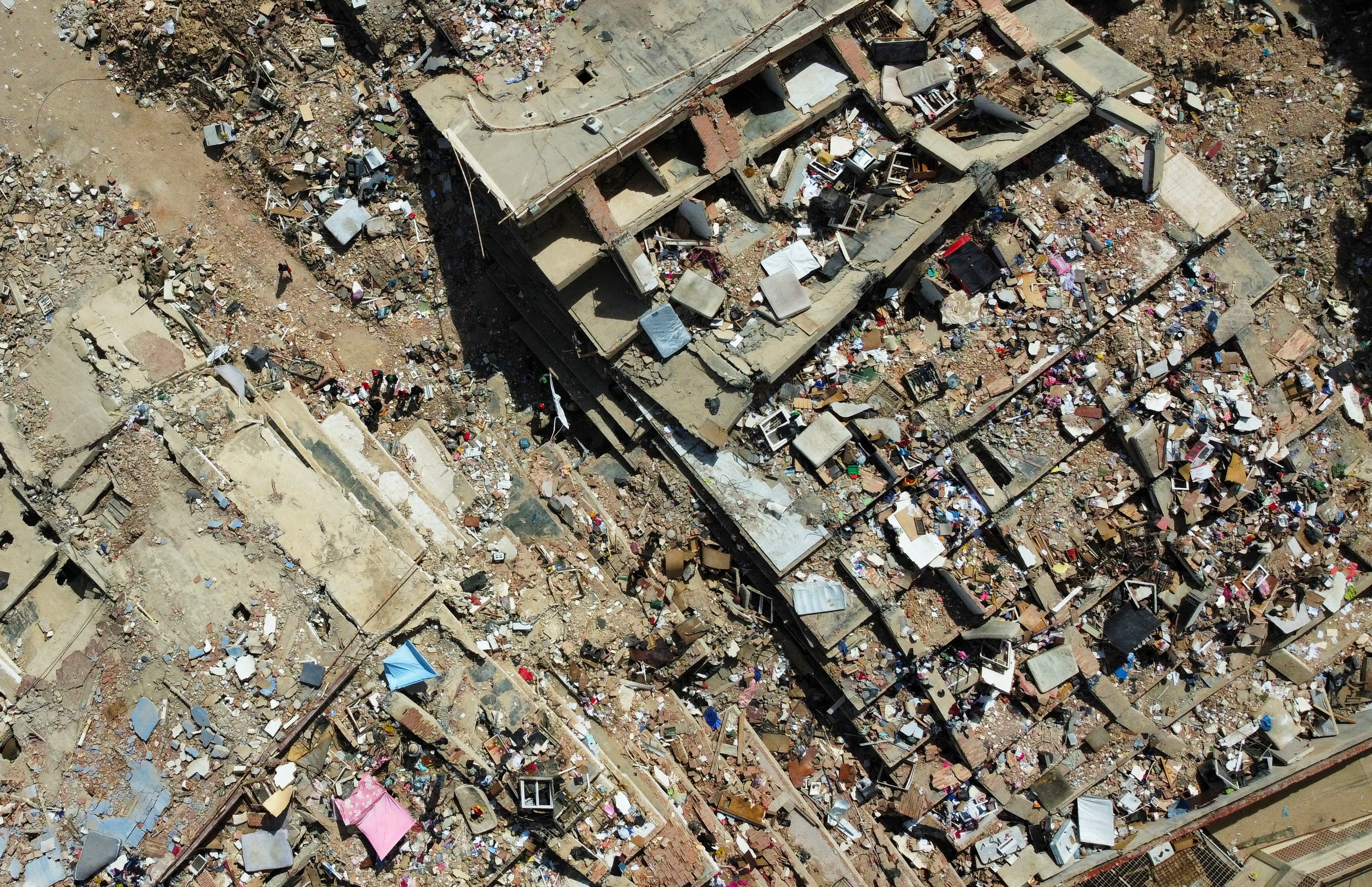 A drone view shows people standing amidst the rubble of a building destroyed by earthquakes, in La Guaira, Venezuela, June 28, 2026.