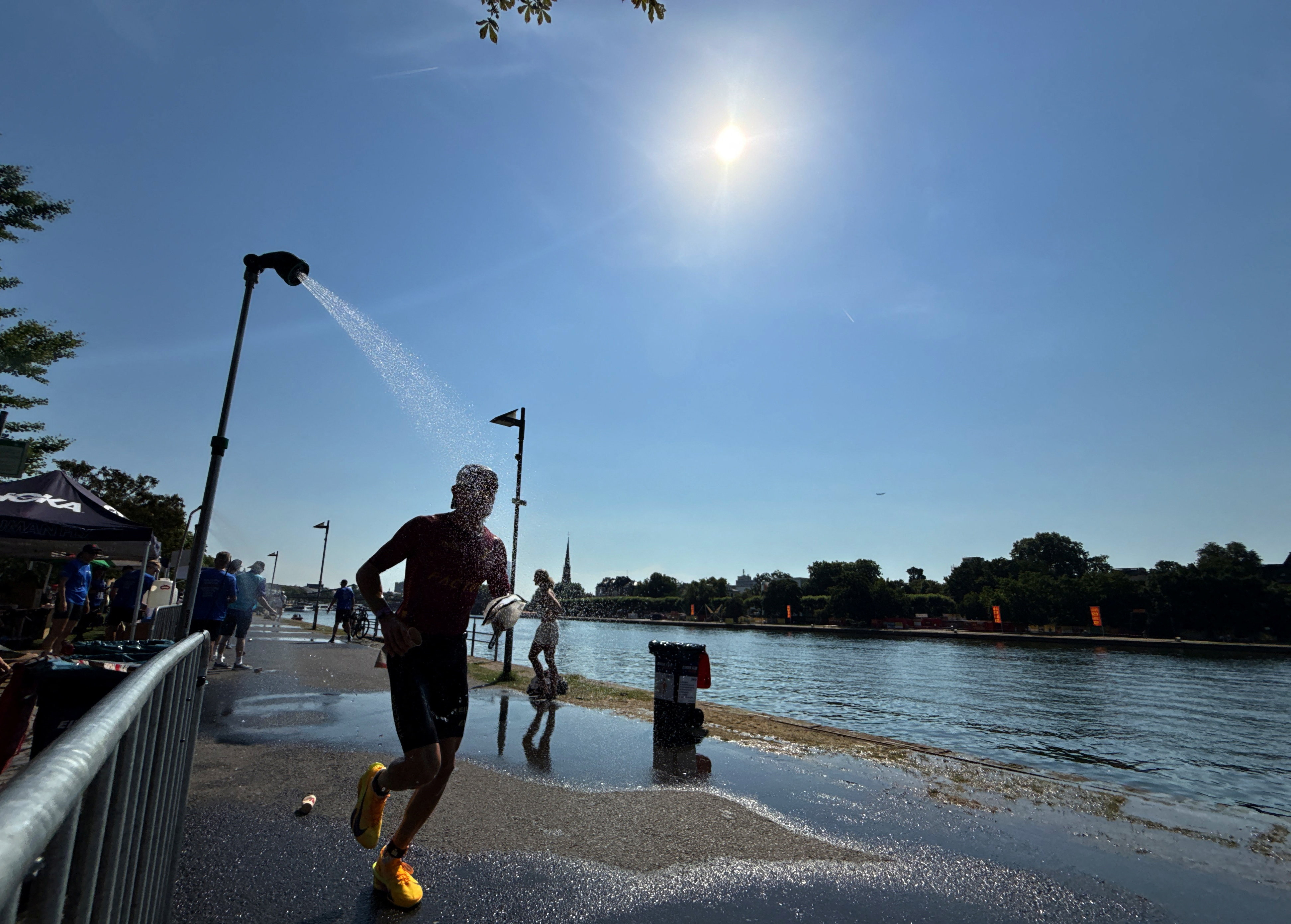 An Ironman athlete runs past a shower near the Main River to cool off during the ongoing heat wave in Frankfurt, Germany, June 28, 2026.   REUTERS/Timm Reichert