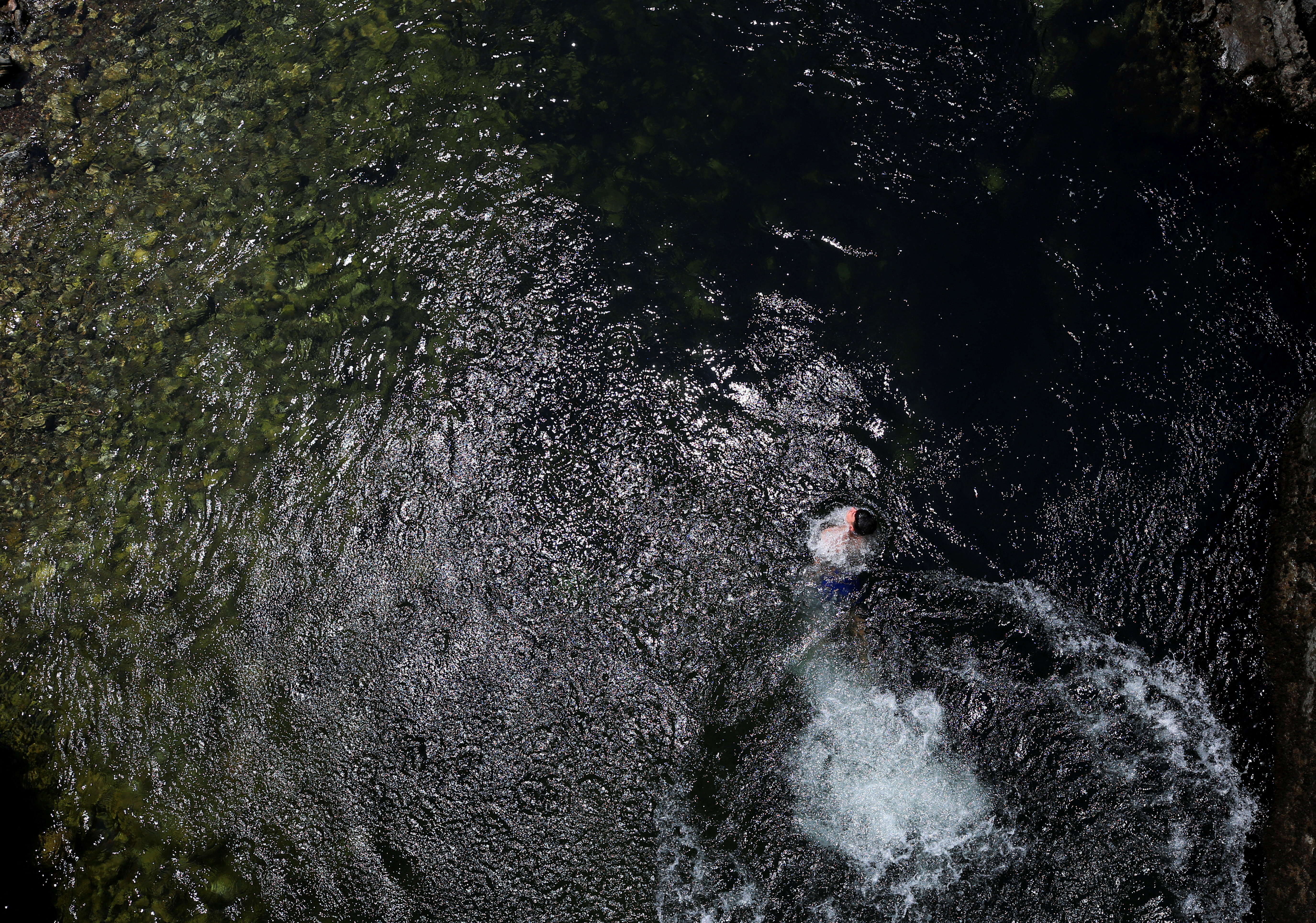 A boy swims in the Treska River after jumping in to cool off from the hot weather near Skopje, North Macedonia, July 19, 2026.