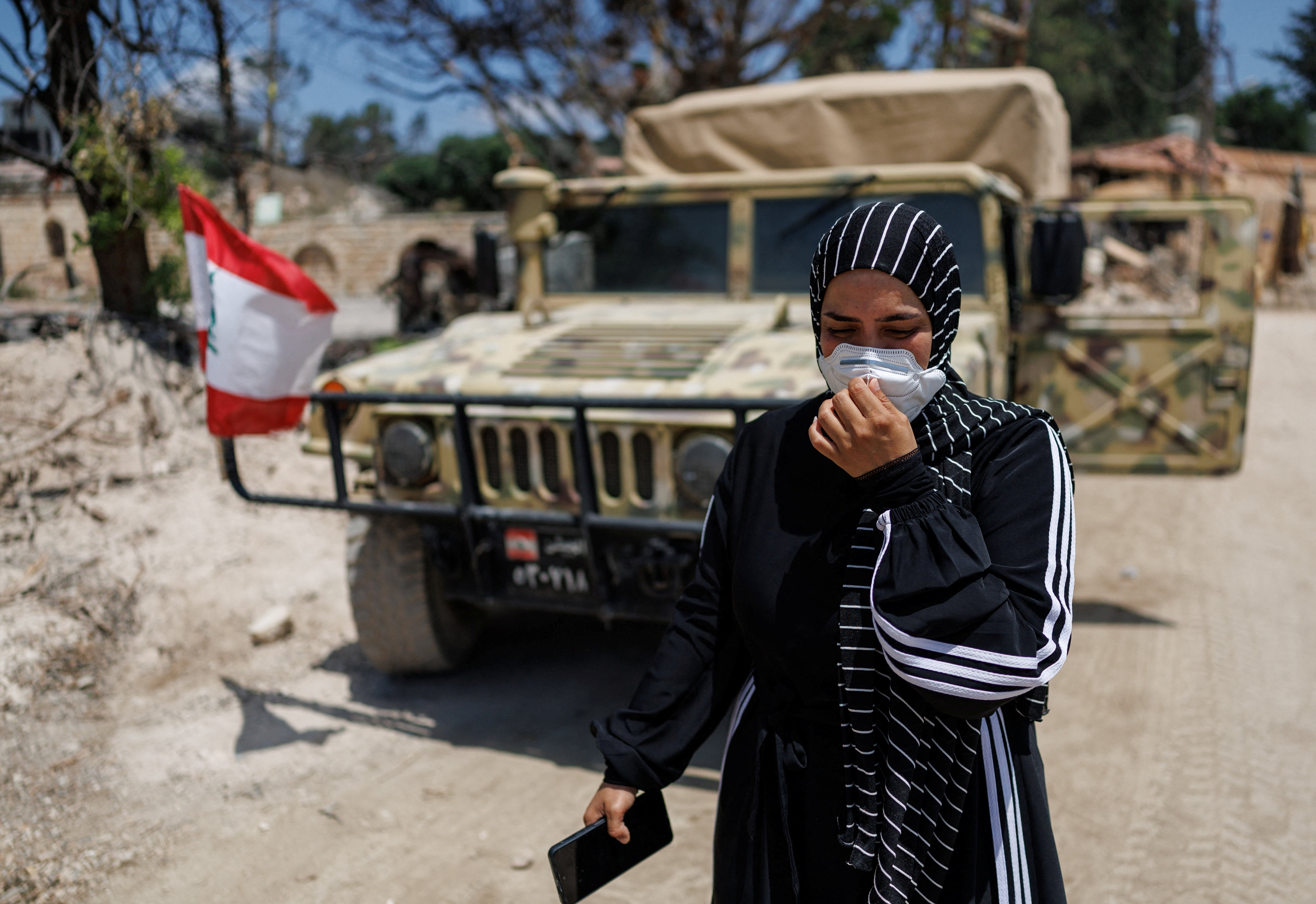 A resident walks past Lebanese army vehicle after returning to Zawtar al-Gharbiyeh, a village in southern Lebanon, following the deployment of Lebanese soldiers
