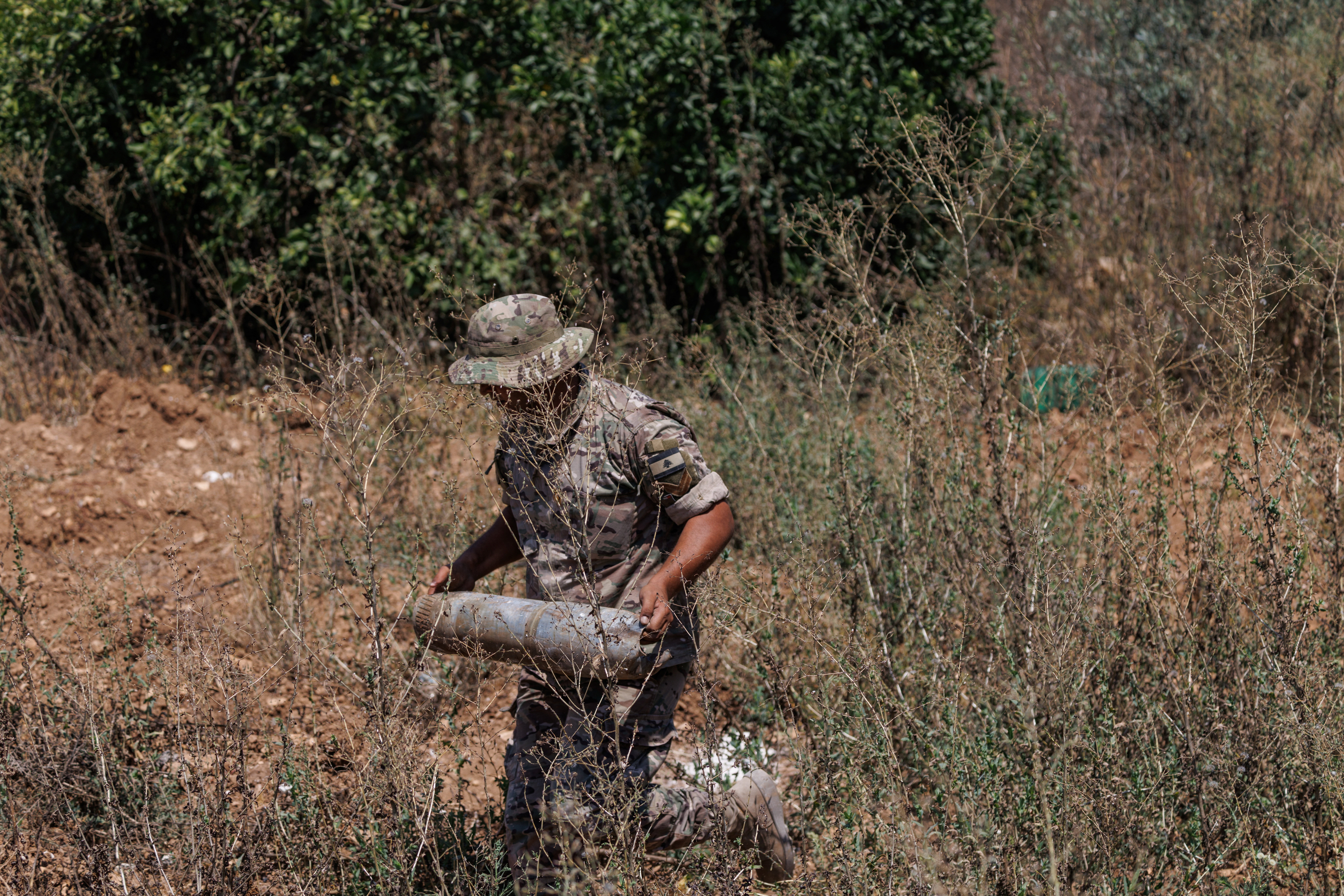 A Lebanese army officer carries an empty shell casing found in a field belonging to a farmer who said it was bulldozed by the Israeli army in Zawtar al-Gharbiyeh