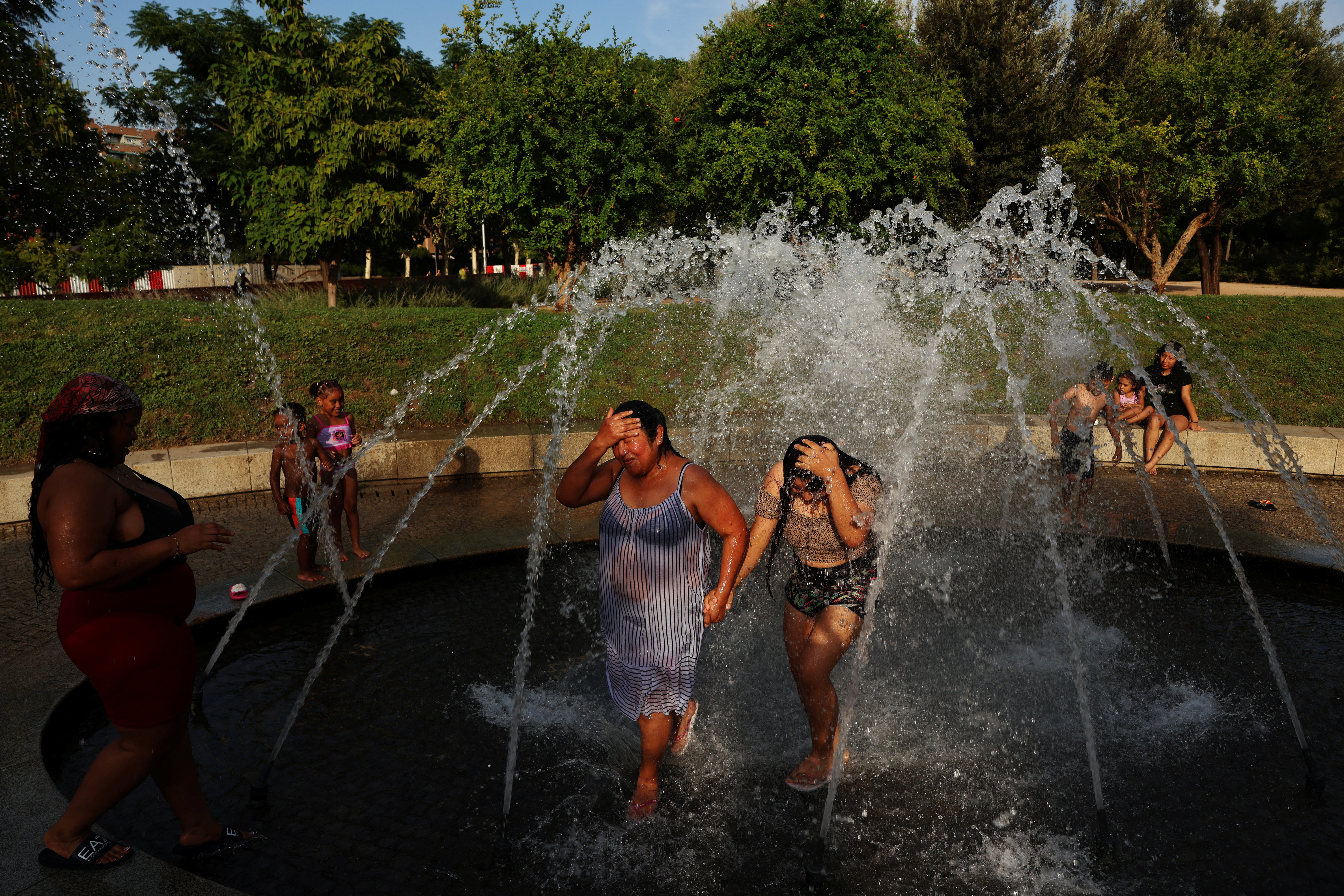 Rebeca Guzman and Jhanines Rivera cool off in a fountain at Madrid Rio park during a heatwave in Madrid, Spain, July 8, 2026. REUTERS/Susana Vera