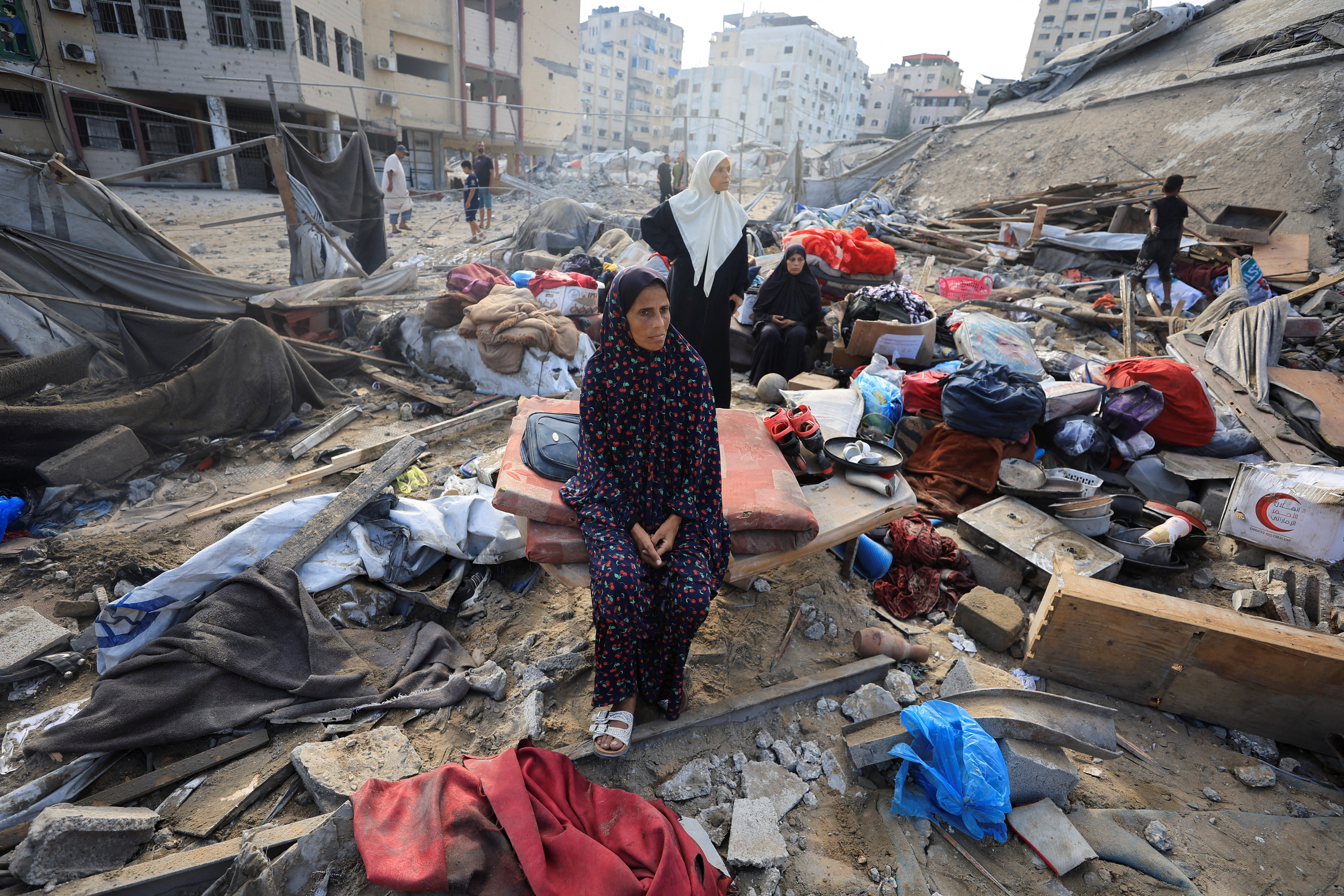 A Palestinian woman sits amidst debris as people inspect the site of Wednesday's Israeli strike on a house whose residents were pre-warned by the Israeli military to evacuate, in Gaza City, July 30, 2026.