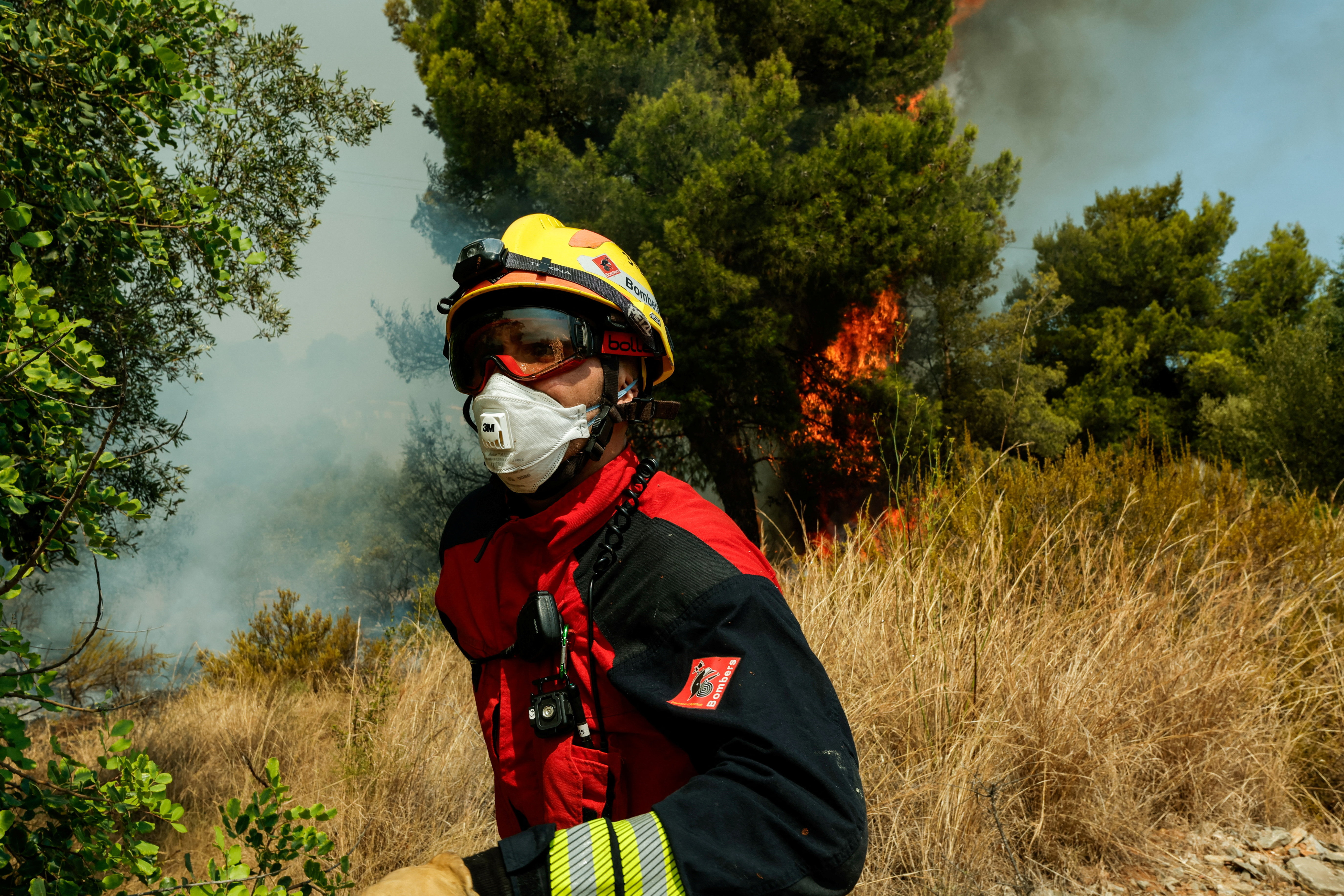 A firefighter walks next to burning bushes during a wildfire in Betxi, Spain, July 26, 2026.