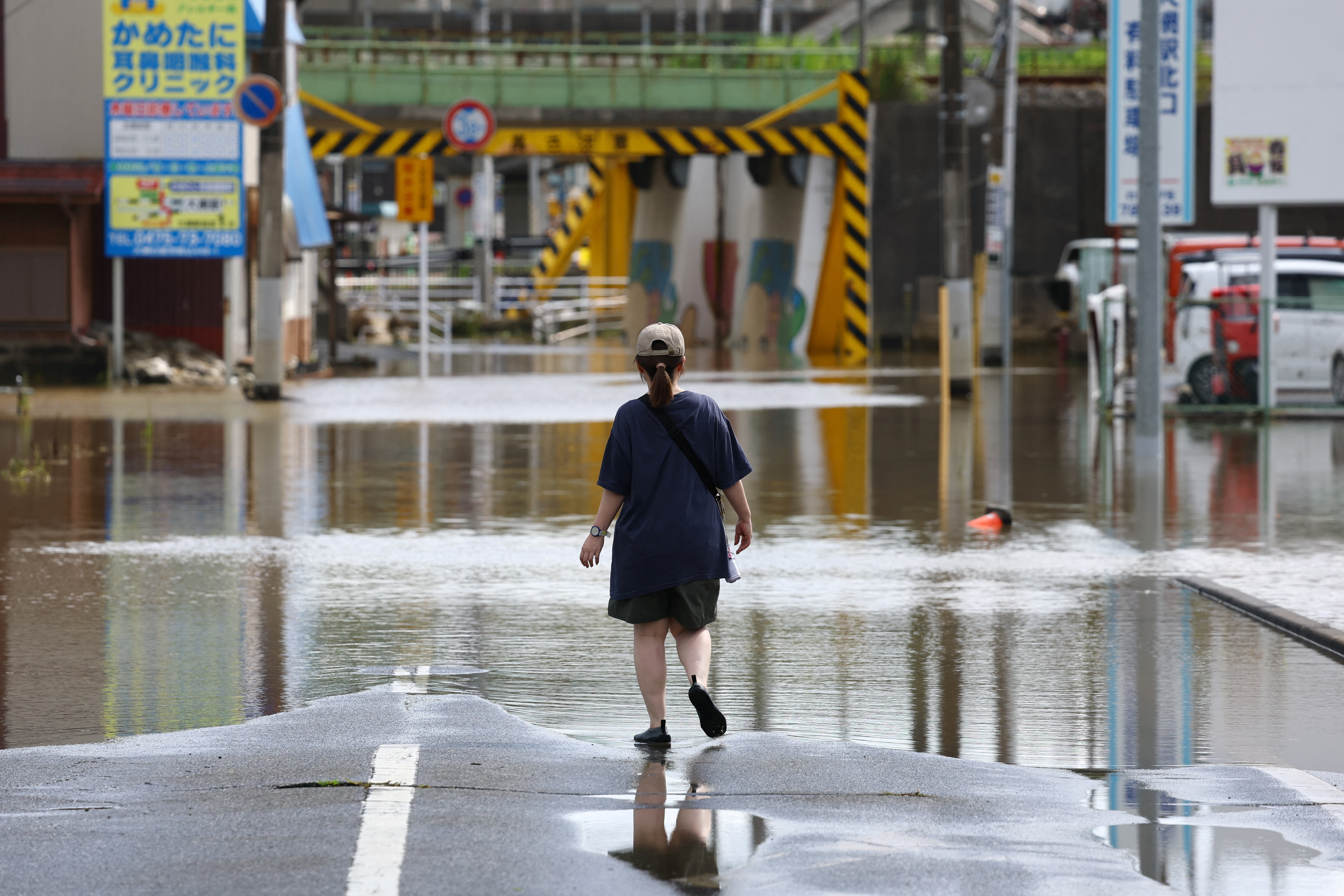 A local resident walks in a flooded area after heavy rain in Oamishirasato. REUTERS/Issei Kato