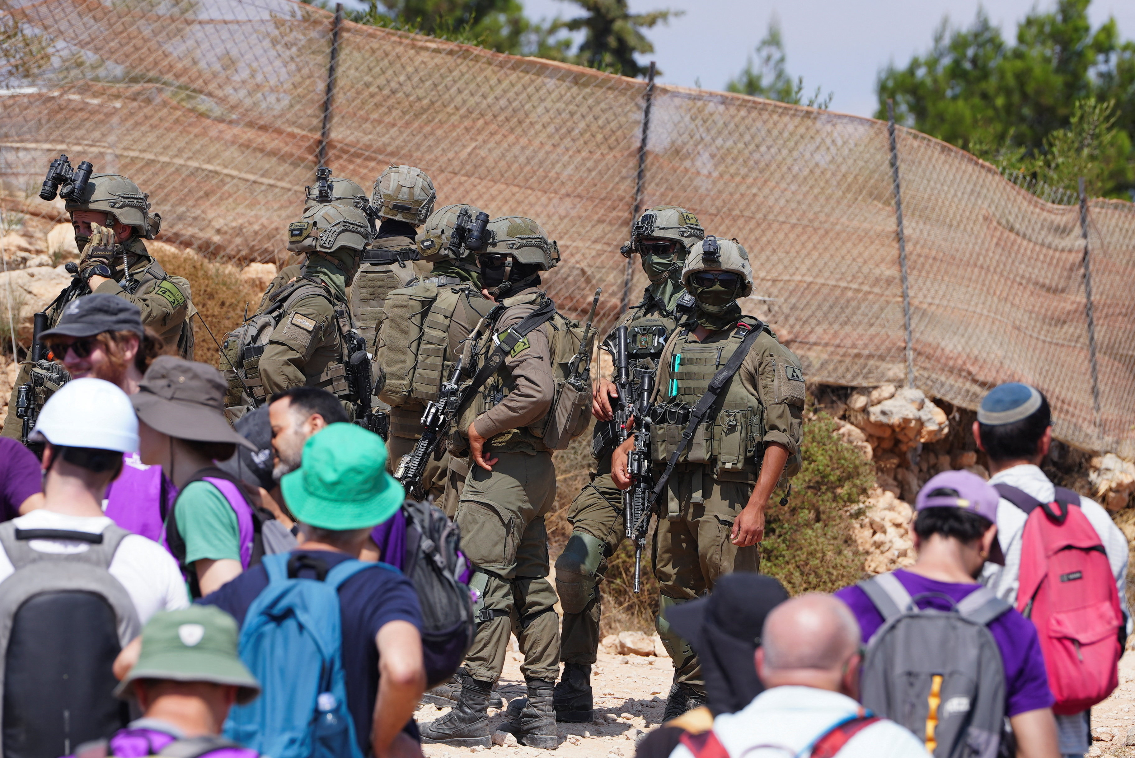 Members of the Israeli security forces stand guard as Palestinian, Israeli and foreign activists try to approach a Palestinian house which was besieged by Israeli settlers, in Qusra