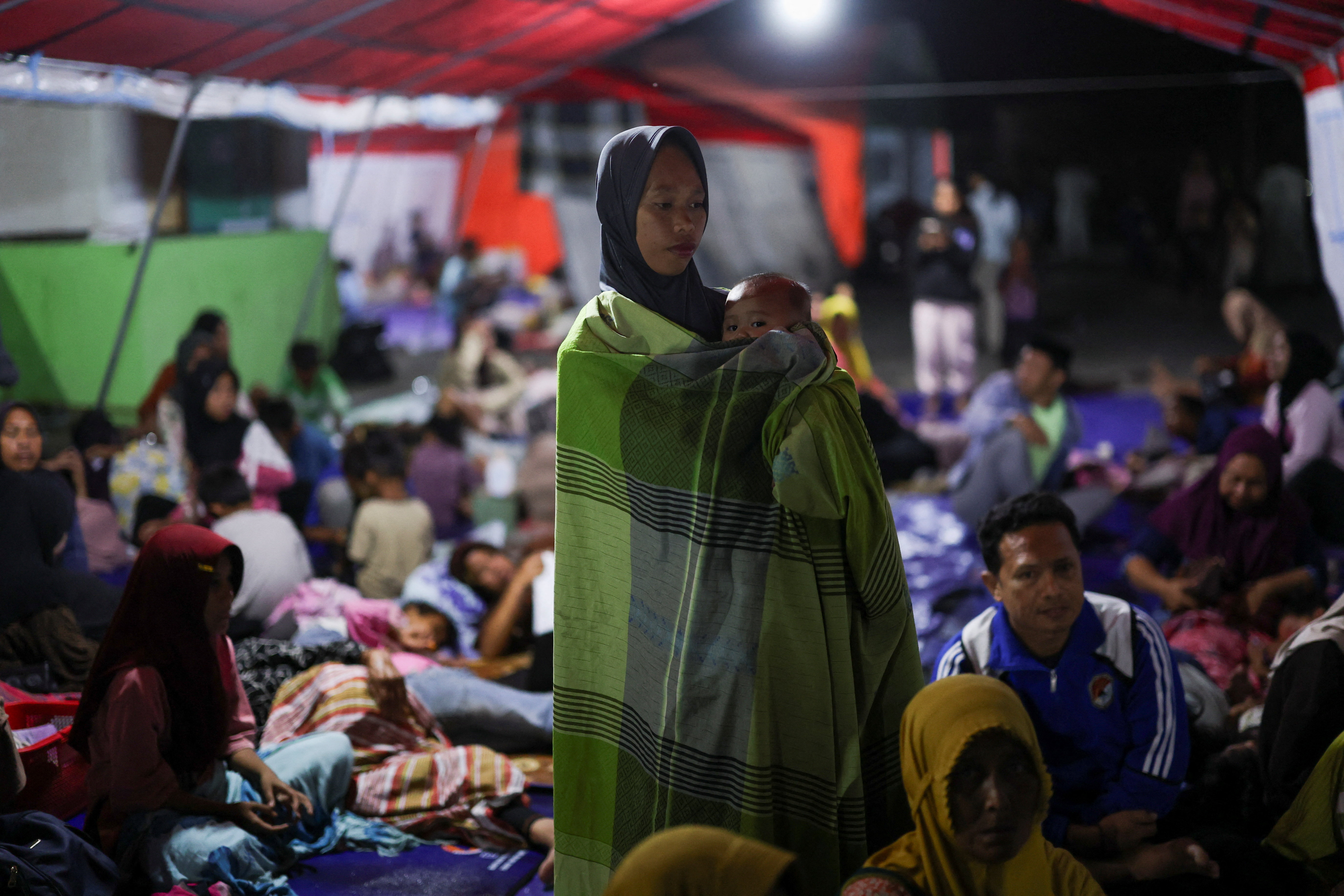 A woman holds a baby as people rest in a shelter. REUTERS/Edgar Su