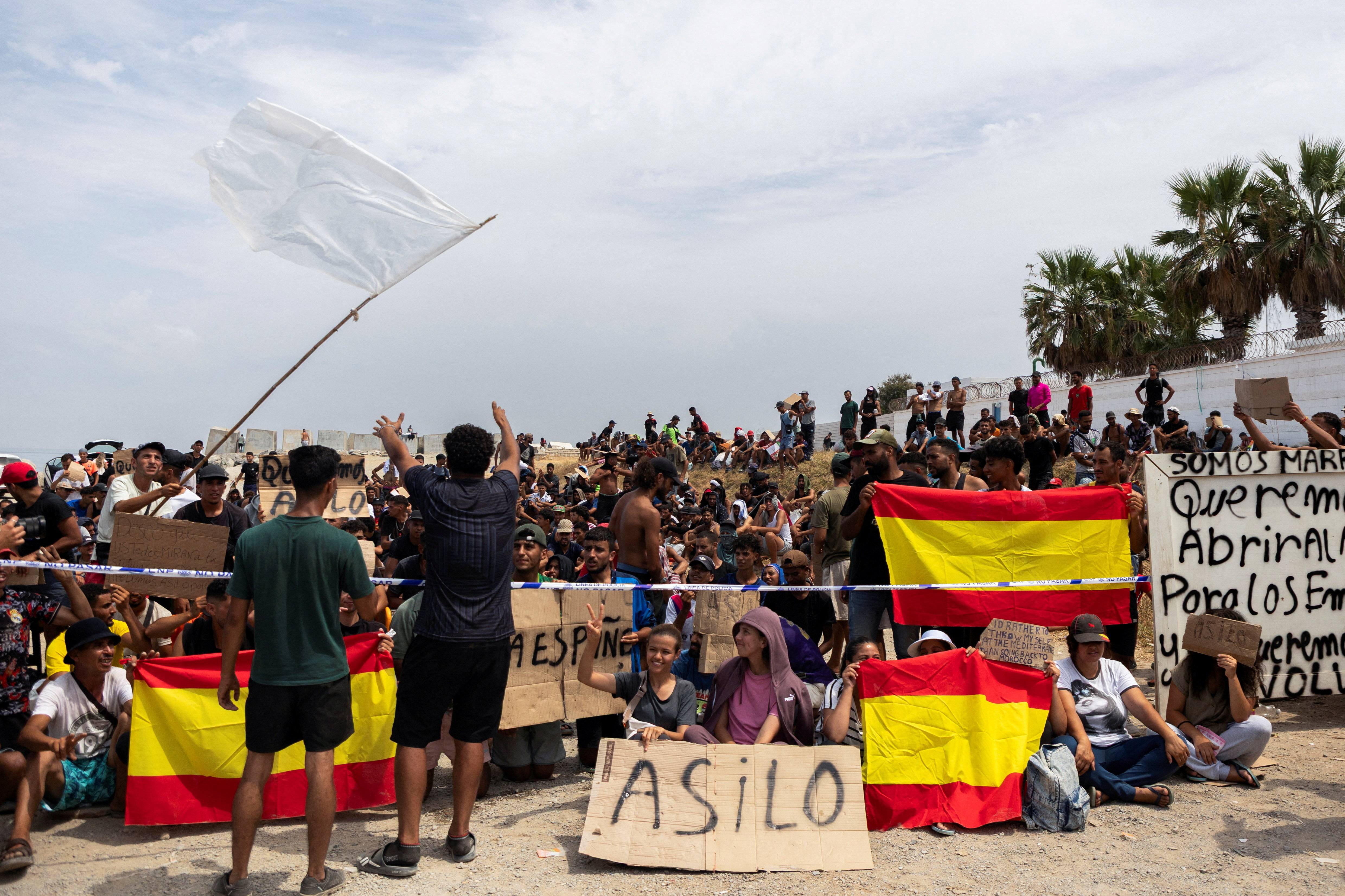 Migrants hold Spanish flags and signs calling for asylum. REUTERS/Maria Alejandra Cardona