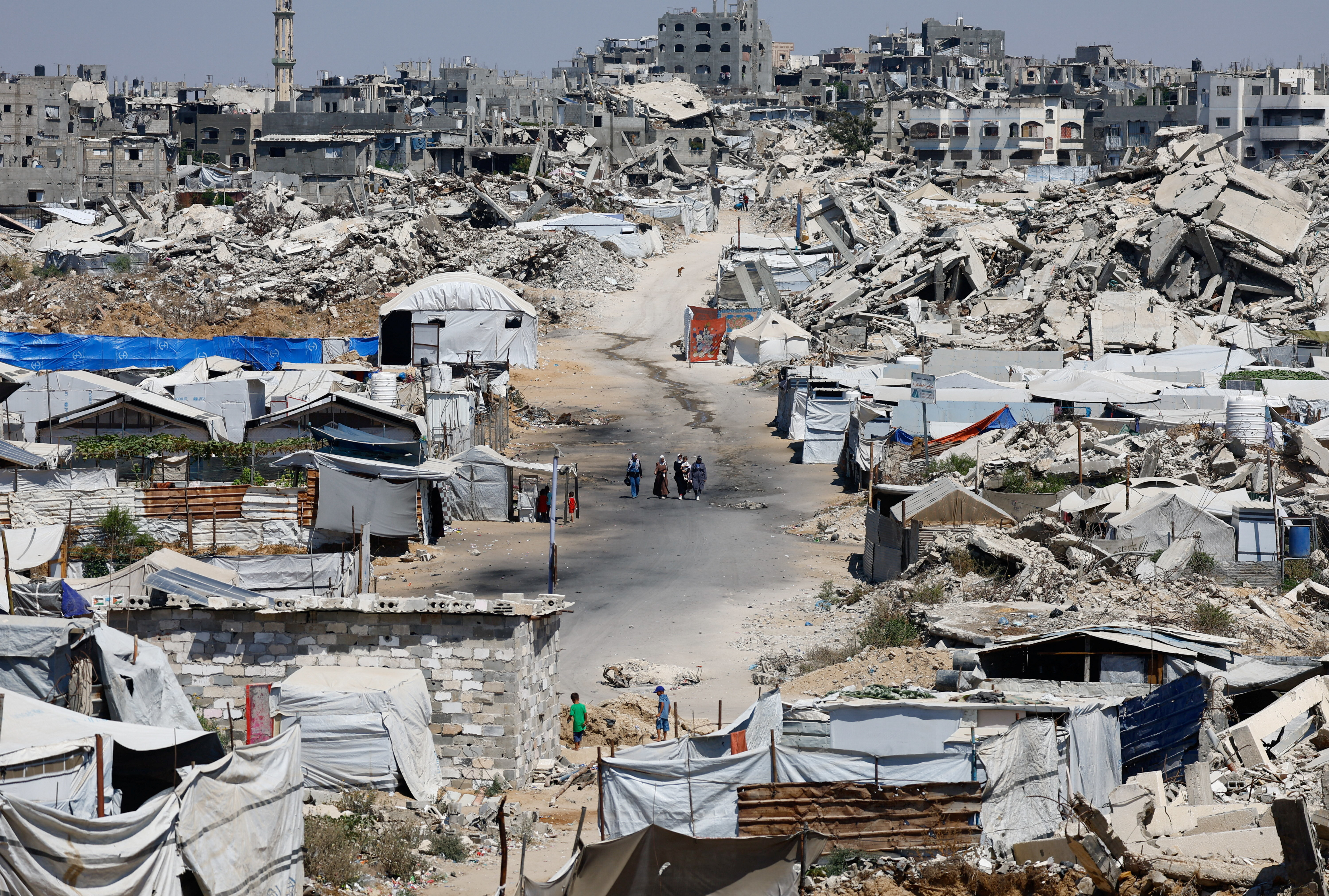 People walk at a site destroyed during the Israeli offensive. REUTERS/Mahmoud Issa