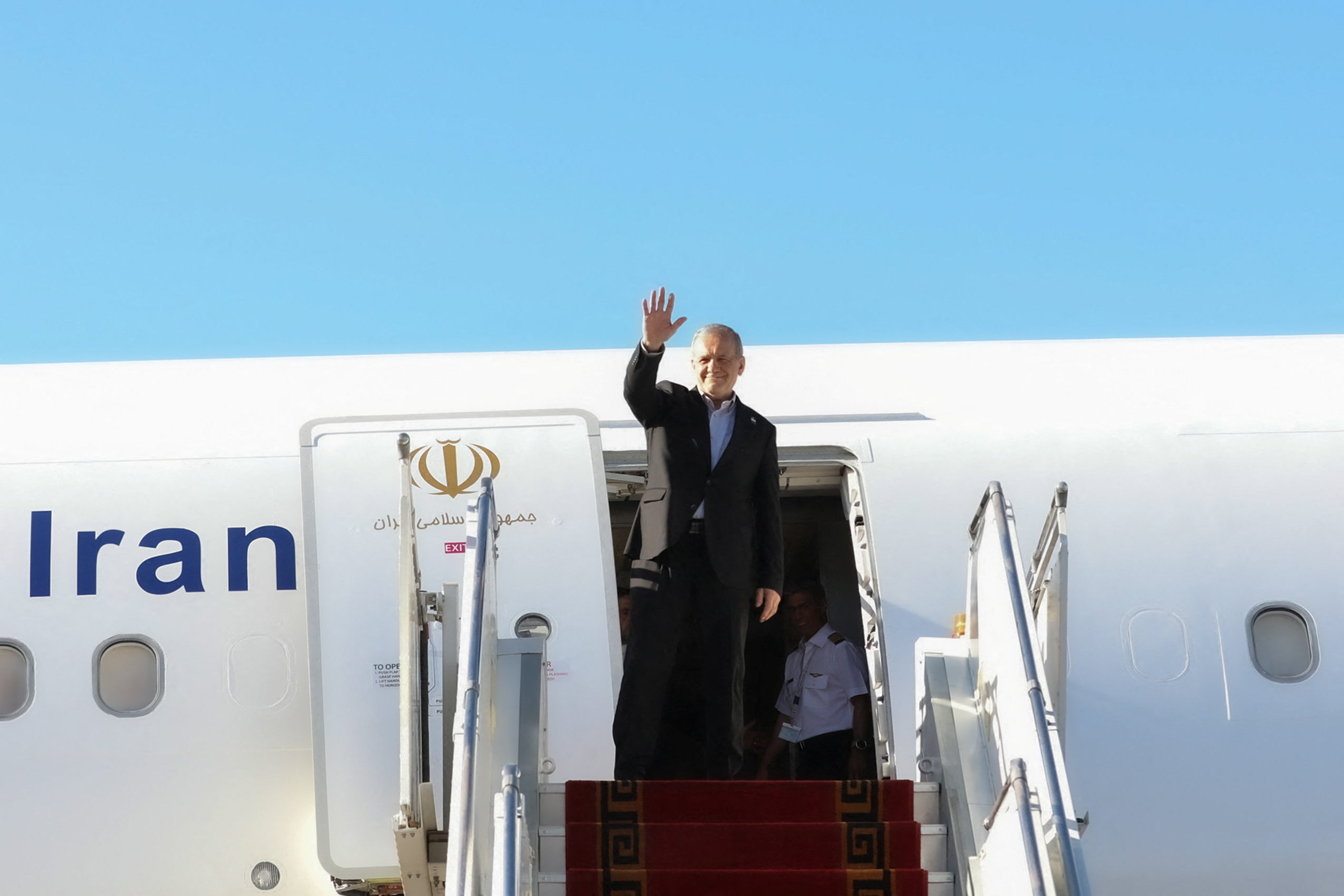 Iranian President Masoud Pezeshkian waves before departing for New York, at Mehrabad Airport in Tehran, Iran