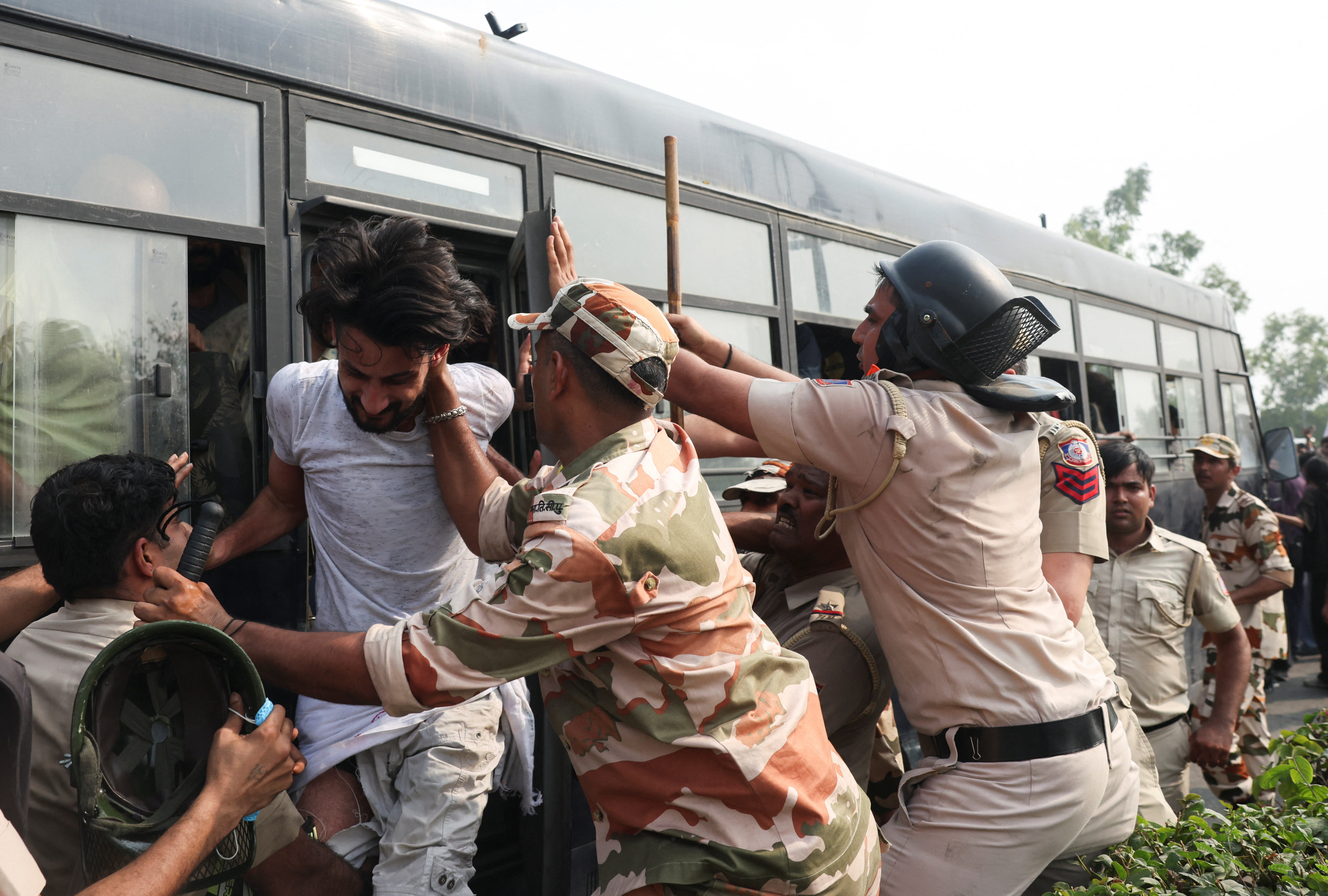 Security personnel try to stop a protester trying to get off the police bus. REUTERS/Priyanshu Singh