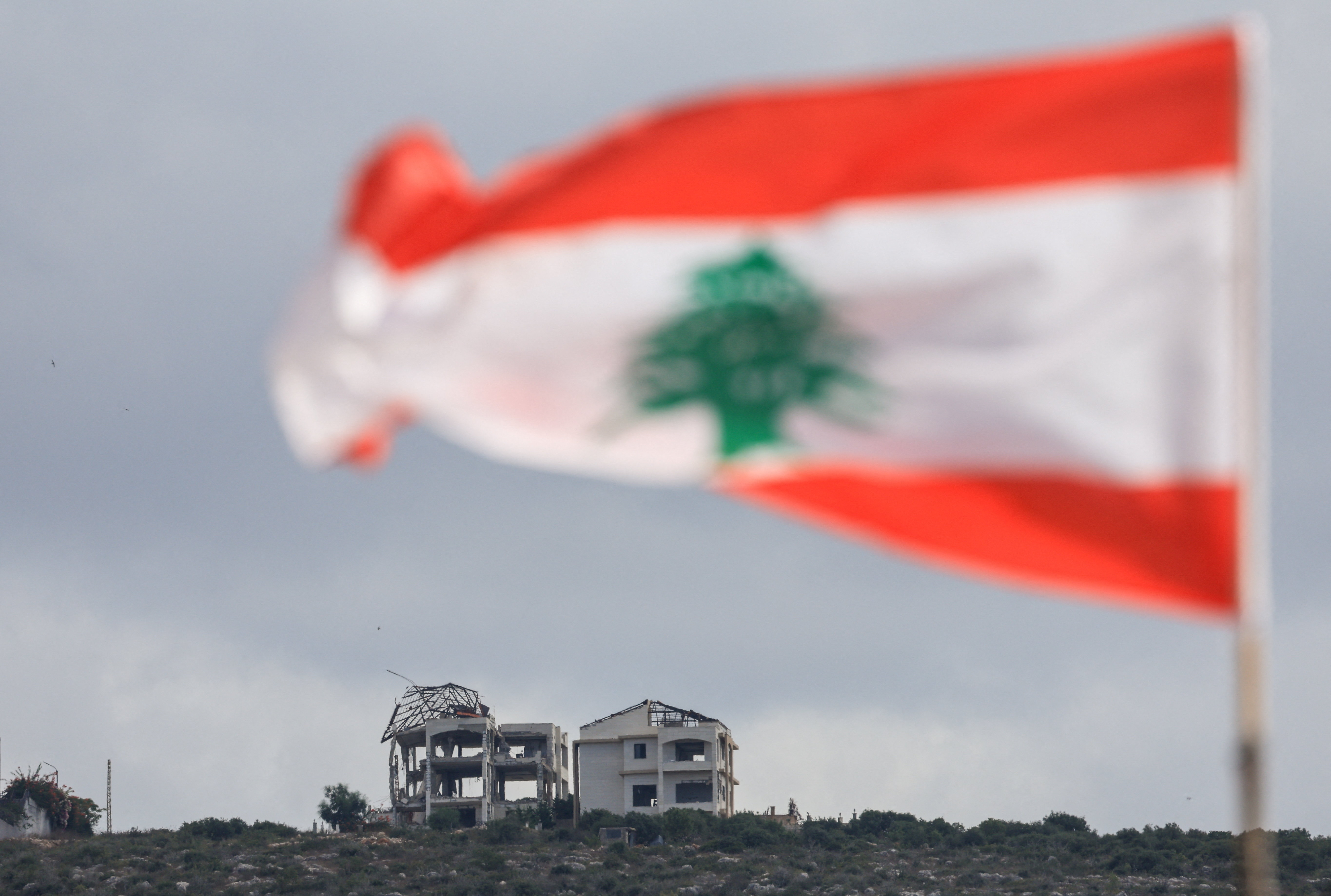 A Lebanese flag flies as buildings lie in ruins in Mansouri, as seen from Henniye, Lebanon, September 29, 2026.
