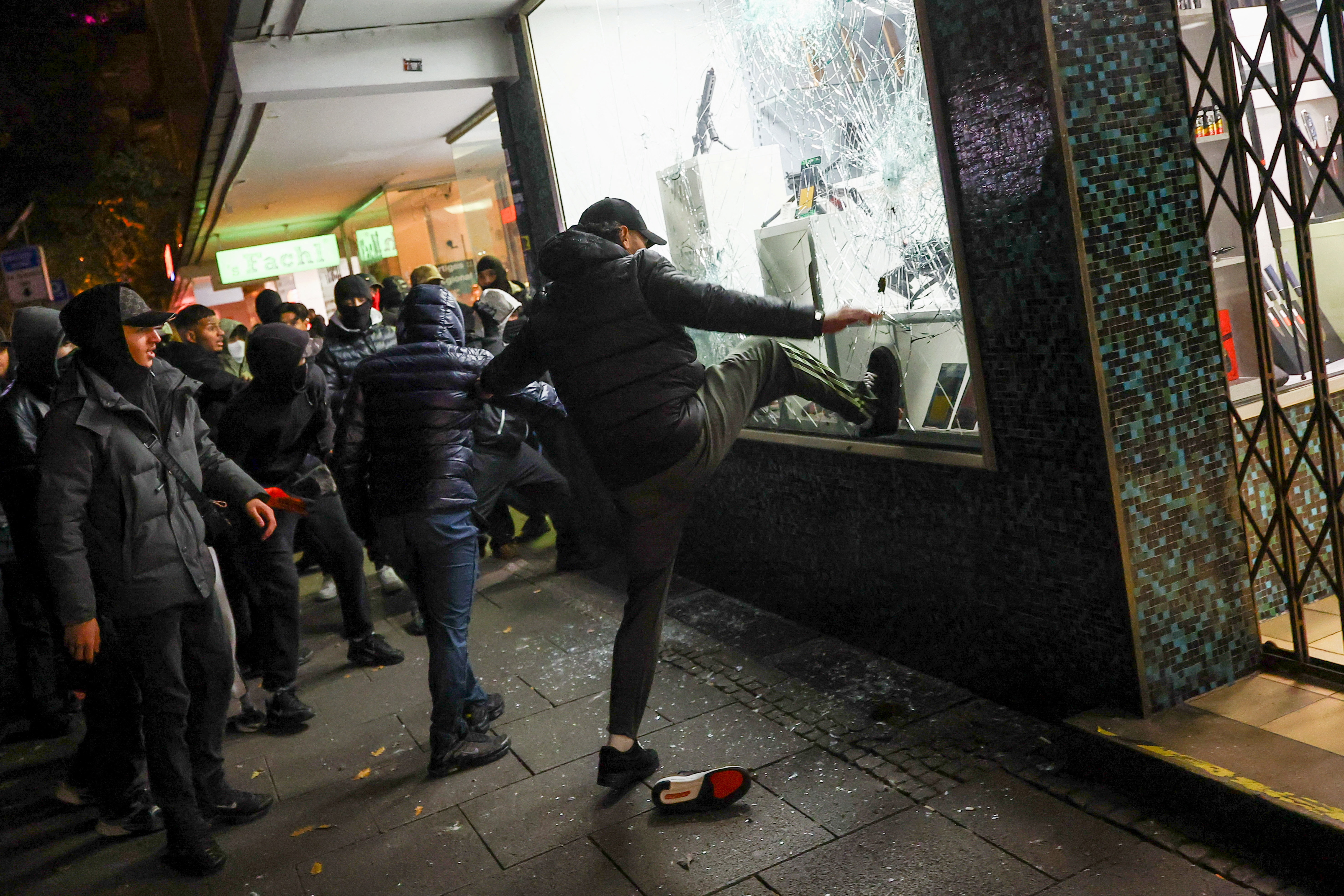People try to break a window of a store selling weapons. REUTERS/Kai Pfaffenbach