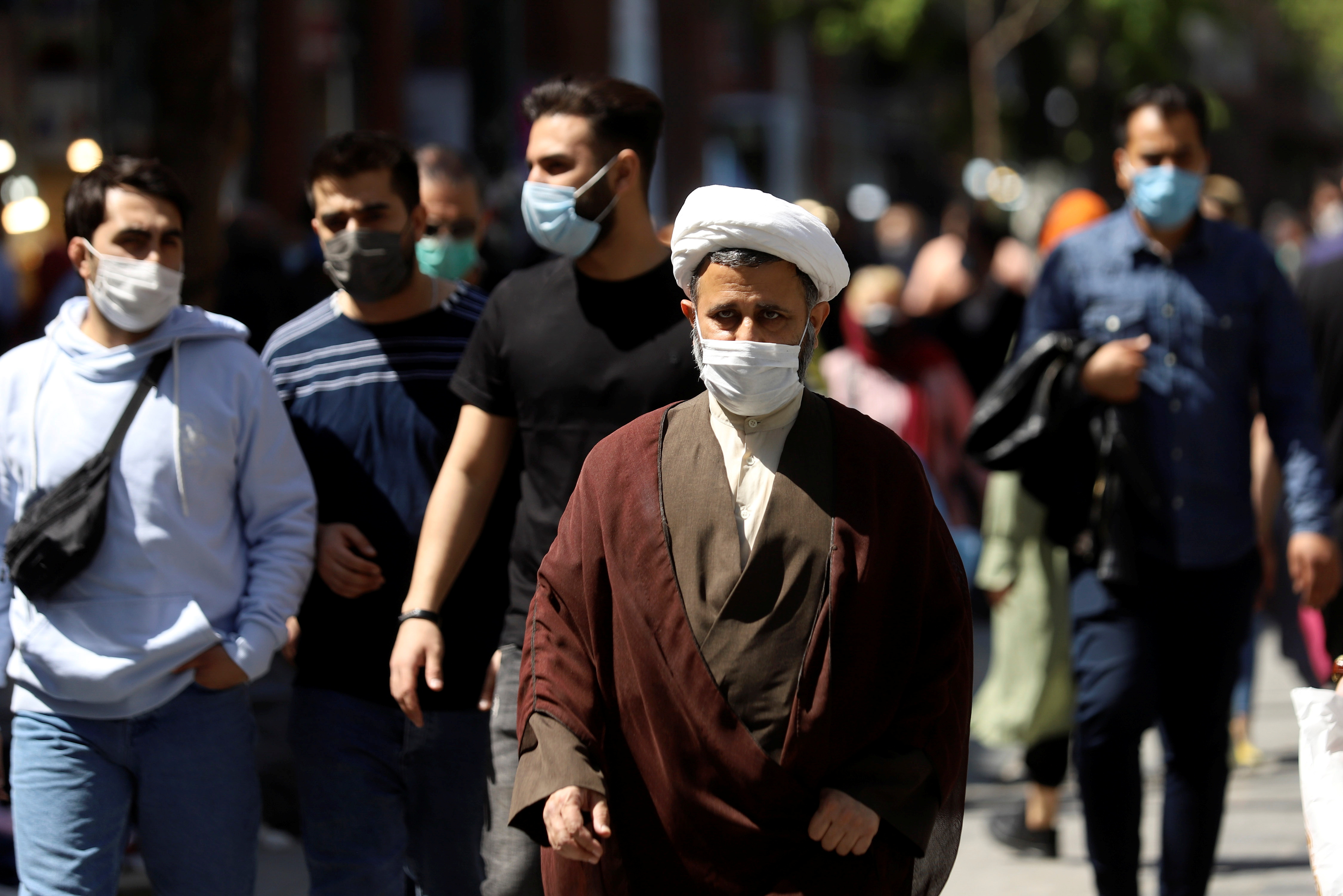 An Iranian cleric wears a protective face mask, as he walks amid the spread of the coronavirus disease (COVID-19), in Tehran