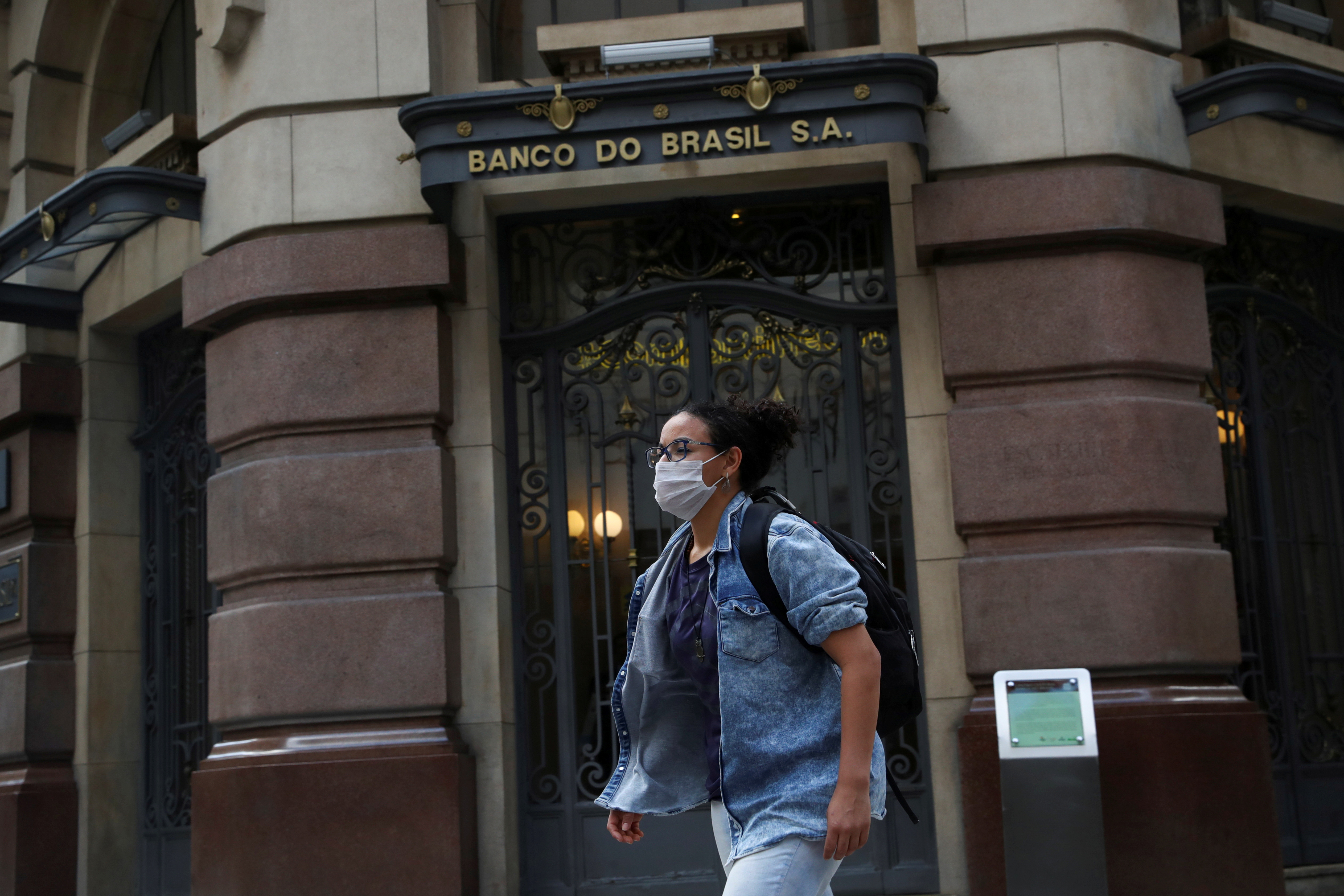 FILE PHOTO: A woman wearing a protective face mask walks in front of Banco do Brasil (Bank of Brazil) cultural building during the coronavirus disease (COVID-19) outbreak in Sao Paulo