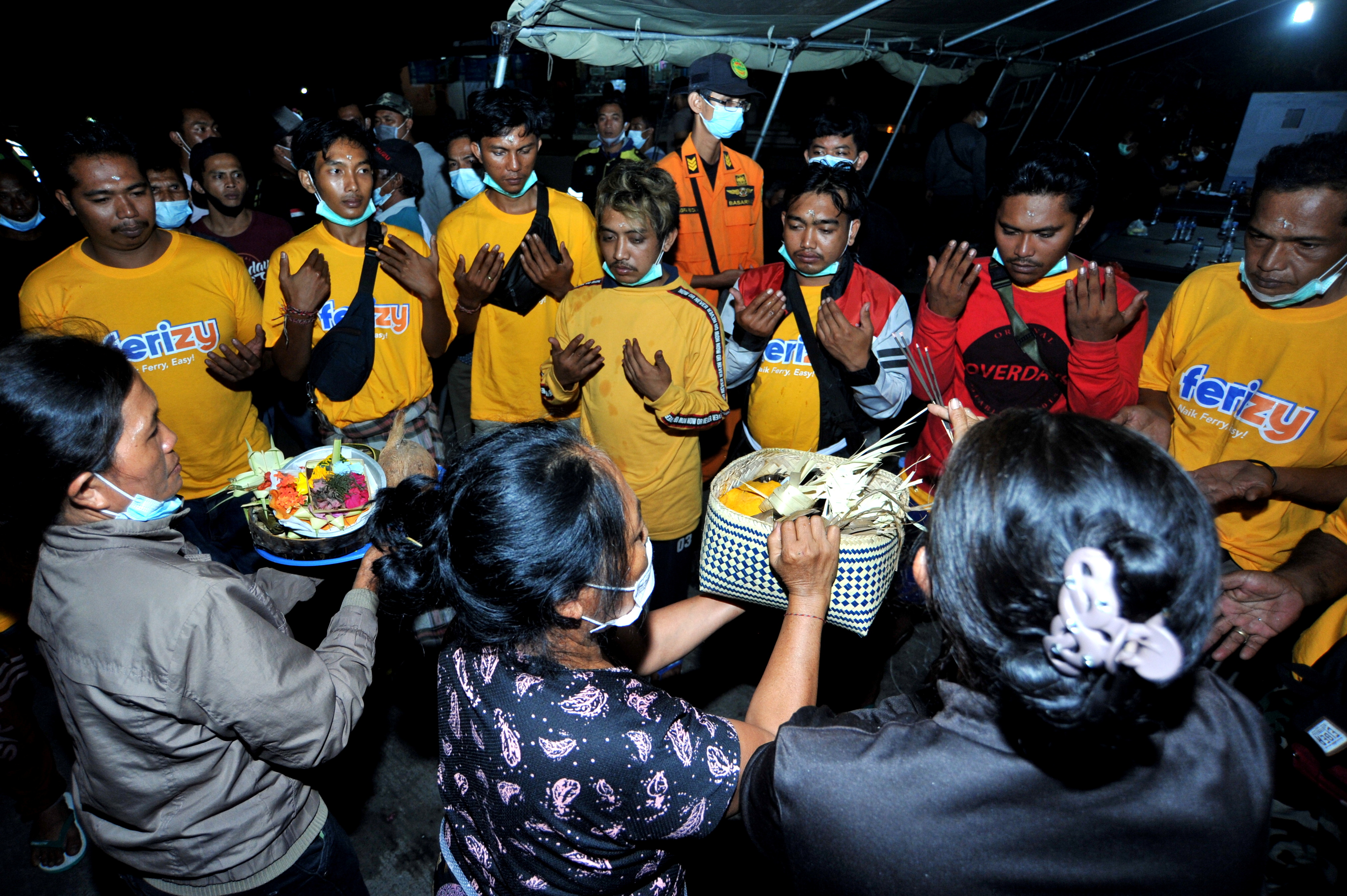 Passengers who survived the sunken ferry KMP Yunice, pray and perform a ritual as they arrive at Gilimanuk port in Bali