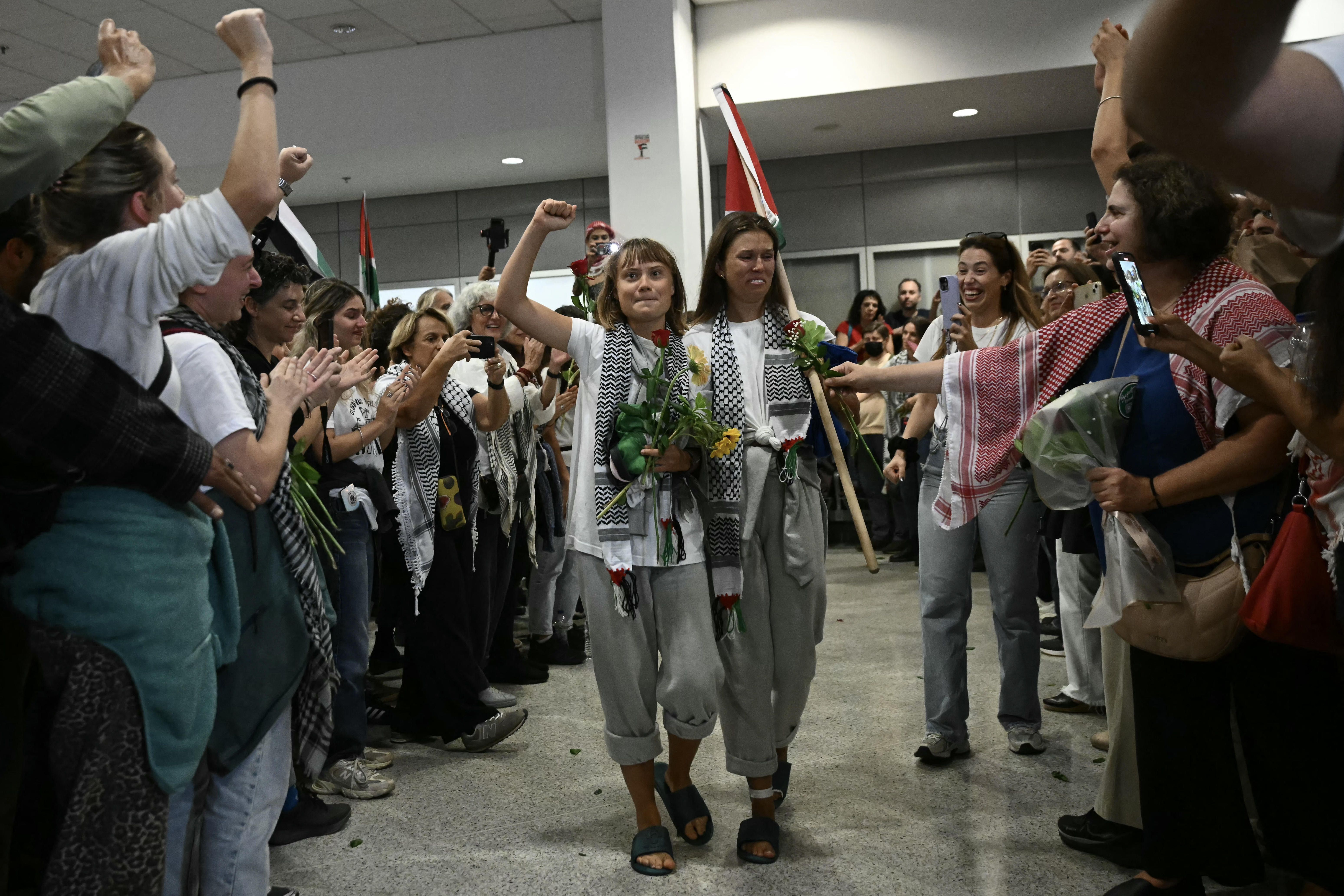 Swedish climate campaigner Greta Thunberg raises her fist, upon arrival alongside activists who were sailing aboard vessels from the Gaza-bound aid flotilla before being stopped and detained by Israeli forces, greeted by a crowd of supporters