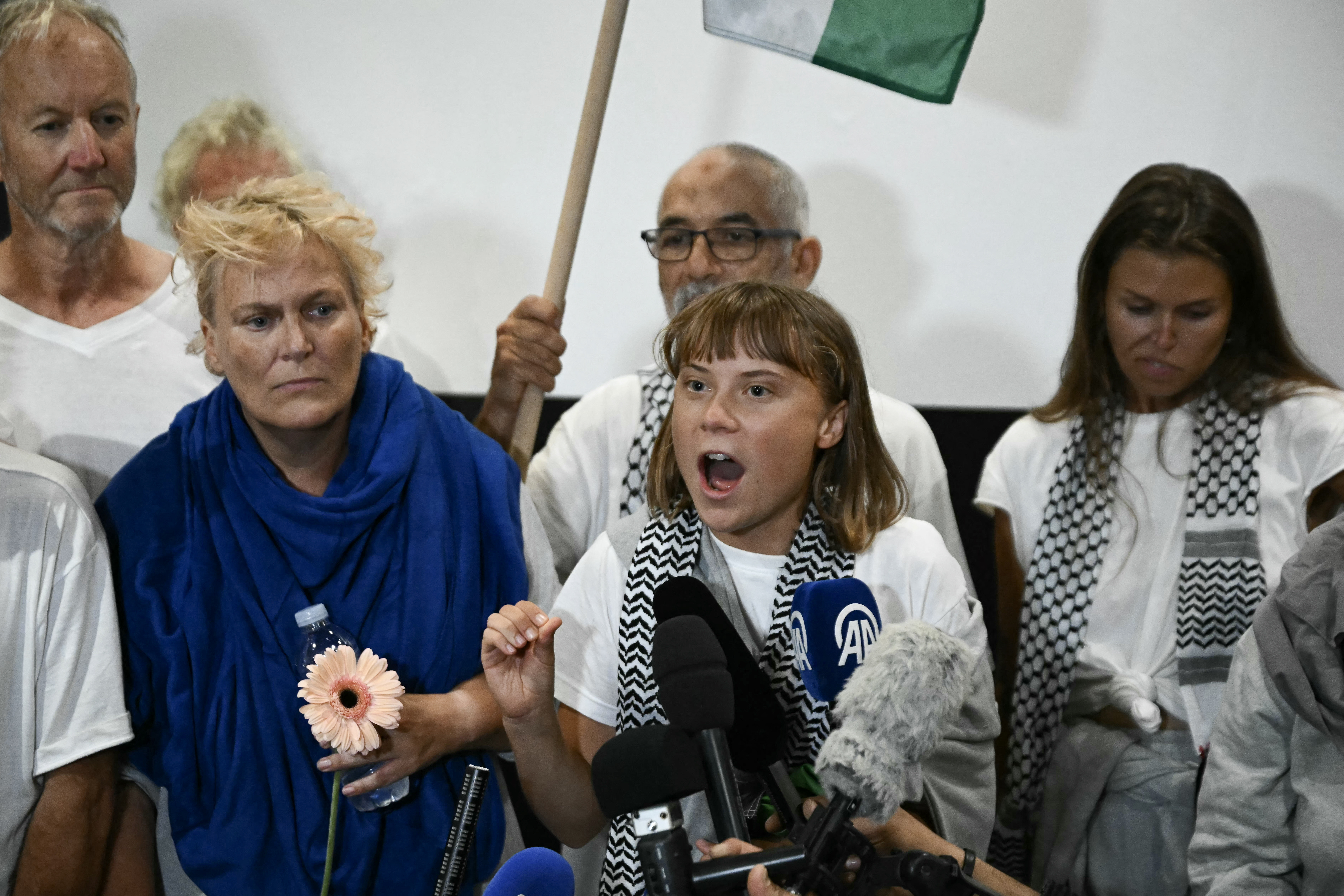 Swedish climate campaigner Greta Thunberg (C) delivers remarks upon arrival alongside activists who were sailing aboard vessels from the Gaza-bound aid flotilla before being stopped and detained by Israeli forces