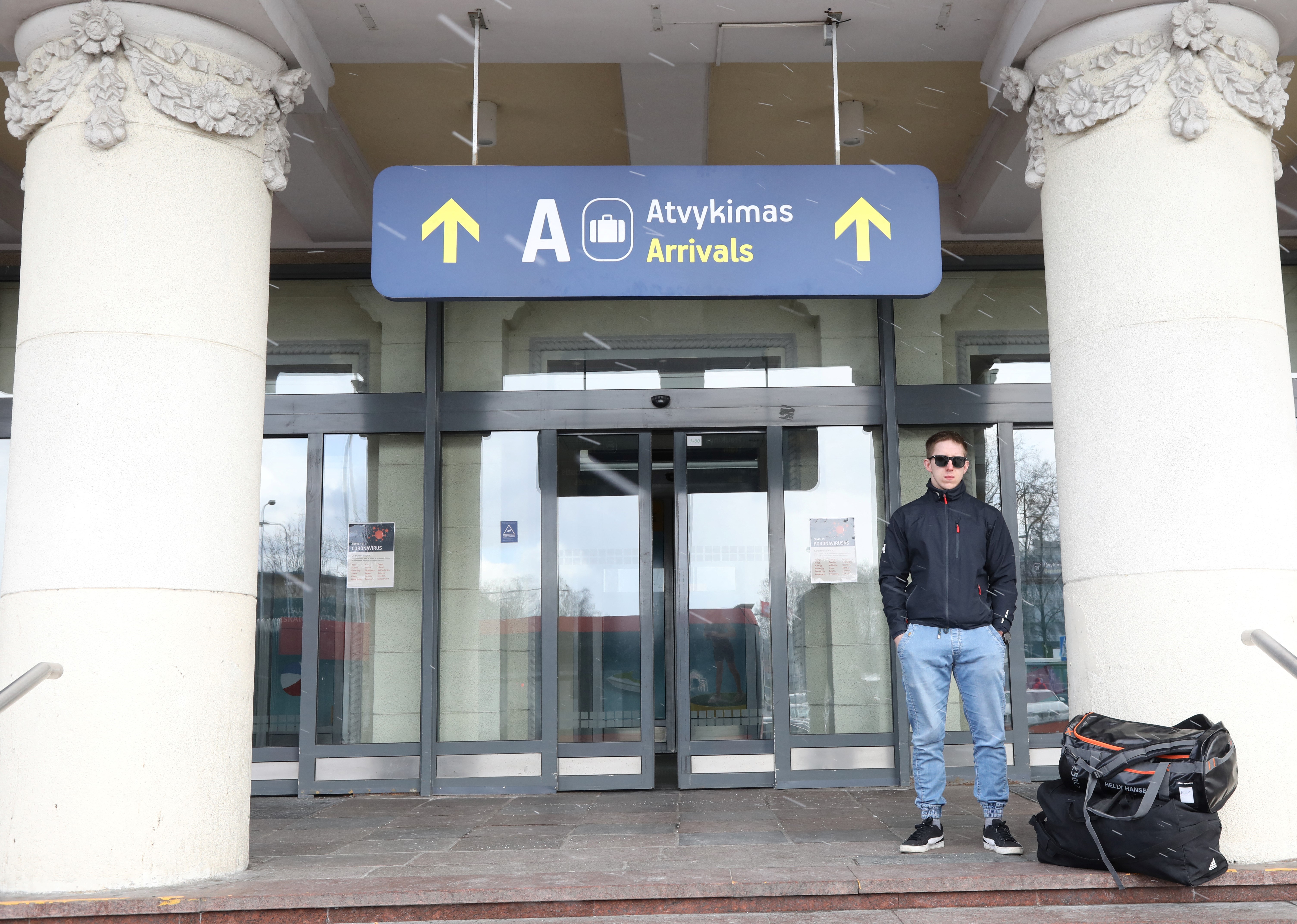 A traveller waits outside Vilnius Airport, in Lithuania, on March 14, 2020. Lithuanian airports started sanitary controls to limit the spread of the novel coronavirus. (Photo by PETRAS MALUKAS / AFP)
