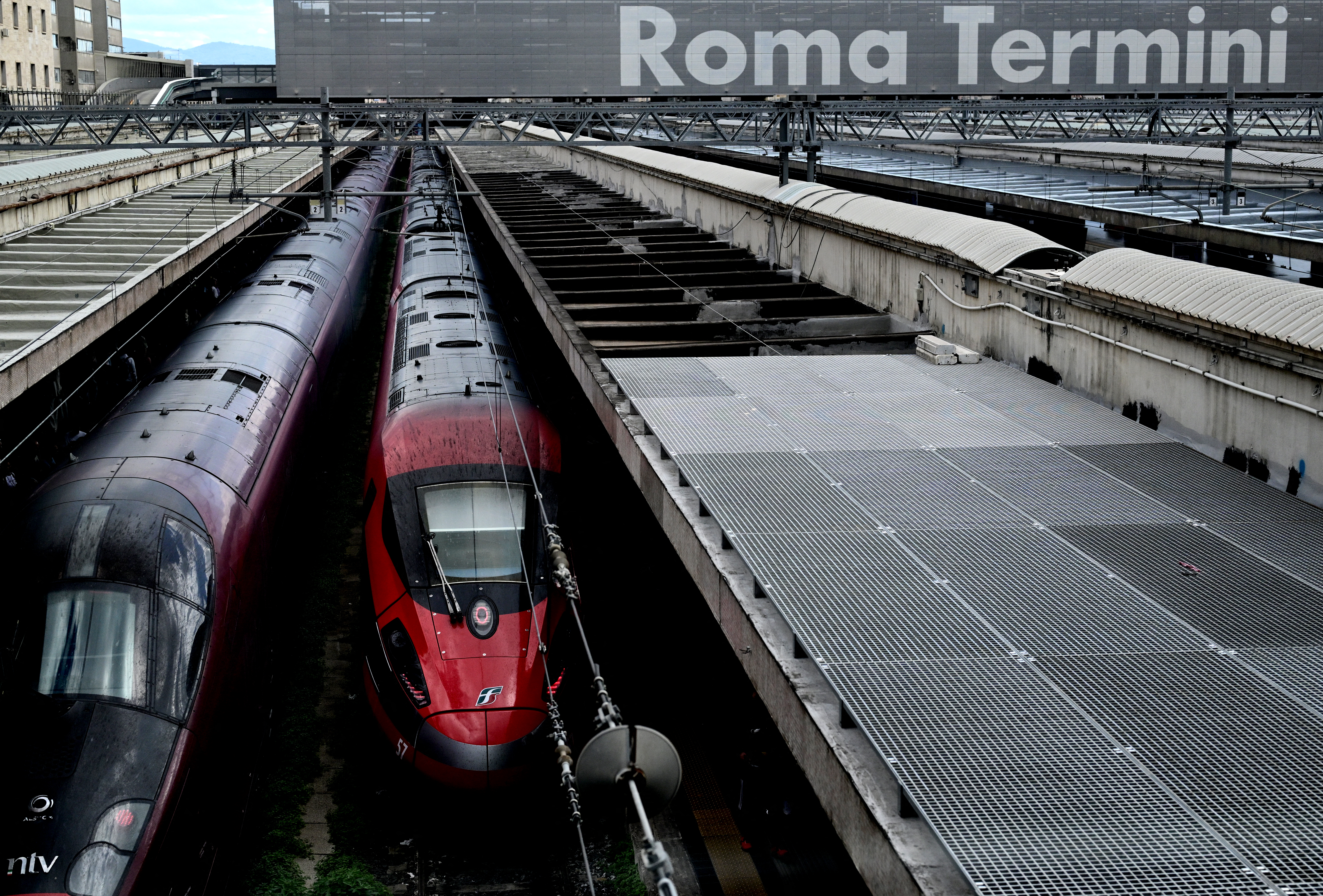 A picture shows an Italo (L) high speed train next to a Trenitalia Frecciarossa train at Roma Termini train station