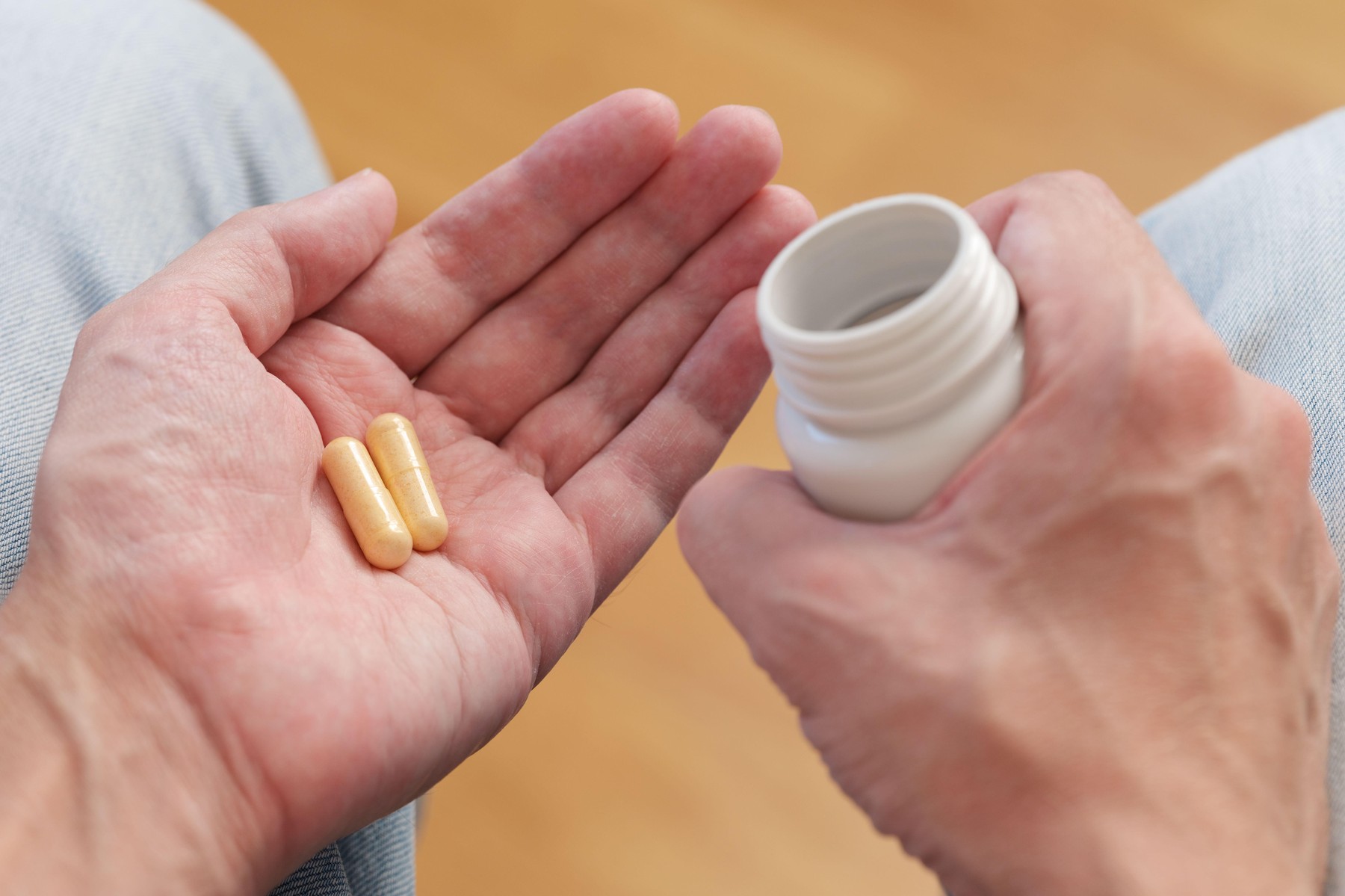 A man poured vitamin B complex pills from a plastic bottle into his palm.
