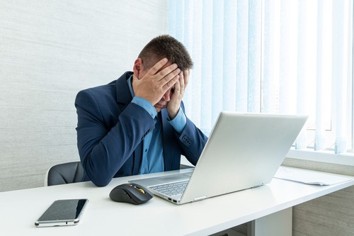 Thoughtful businessman looking at his laptop. a tired employee at work in front of a computer monitor. annoying work. A sad businessman. Tired eyesigh