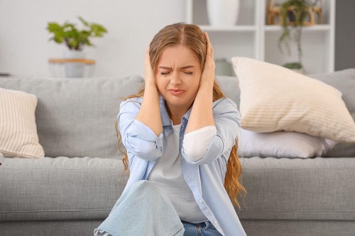 Young woman suffering from loud neighbours at home