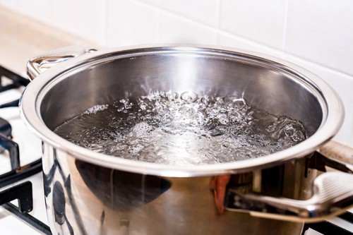 Boiling water for soup in modern saucepan