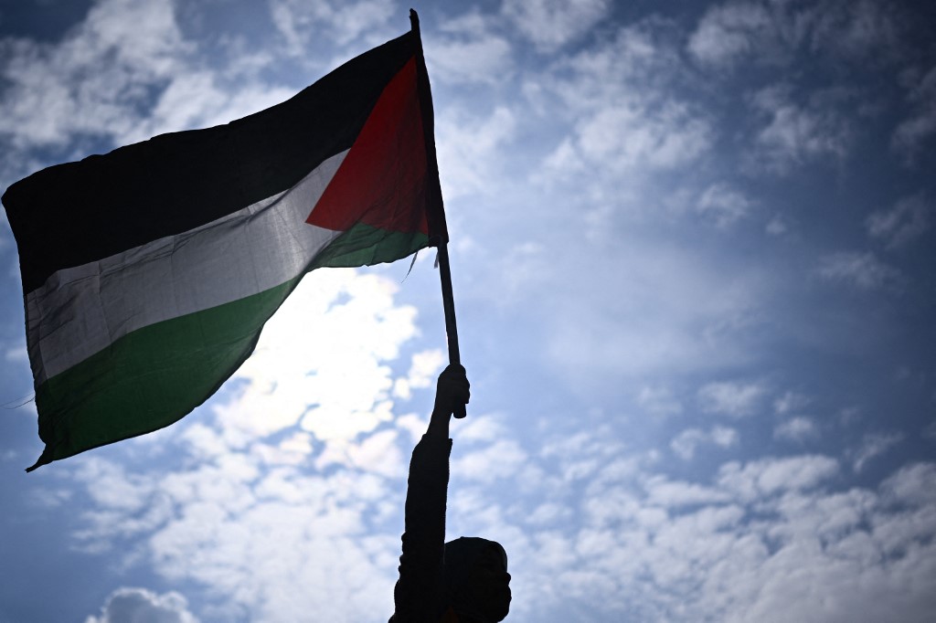A protester holds a Palestinian flag during a rally called by several French organisations in support of Palestinian people at Place de la Republique in Paris