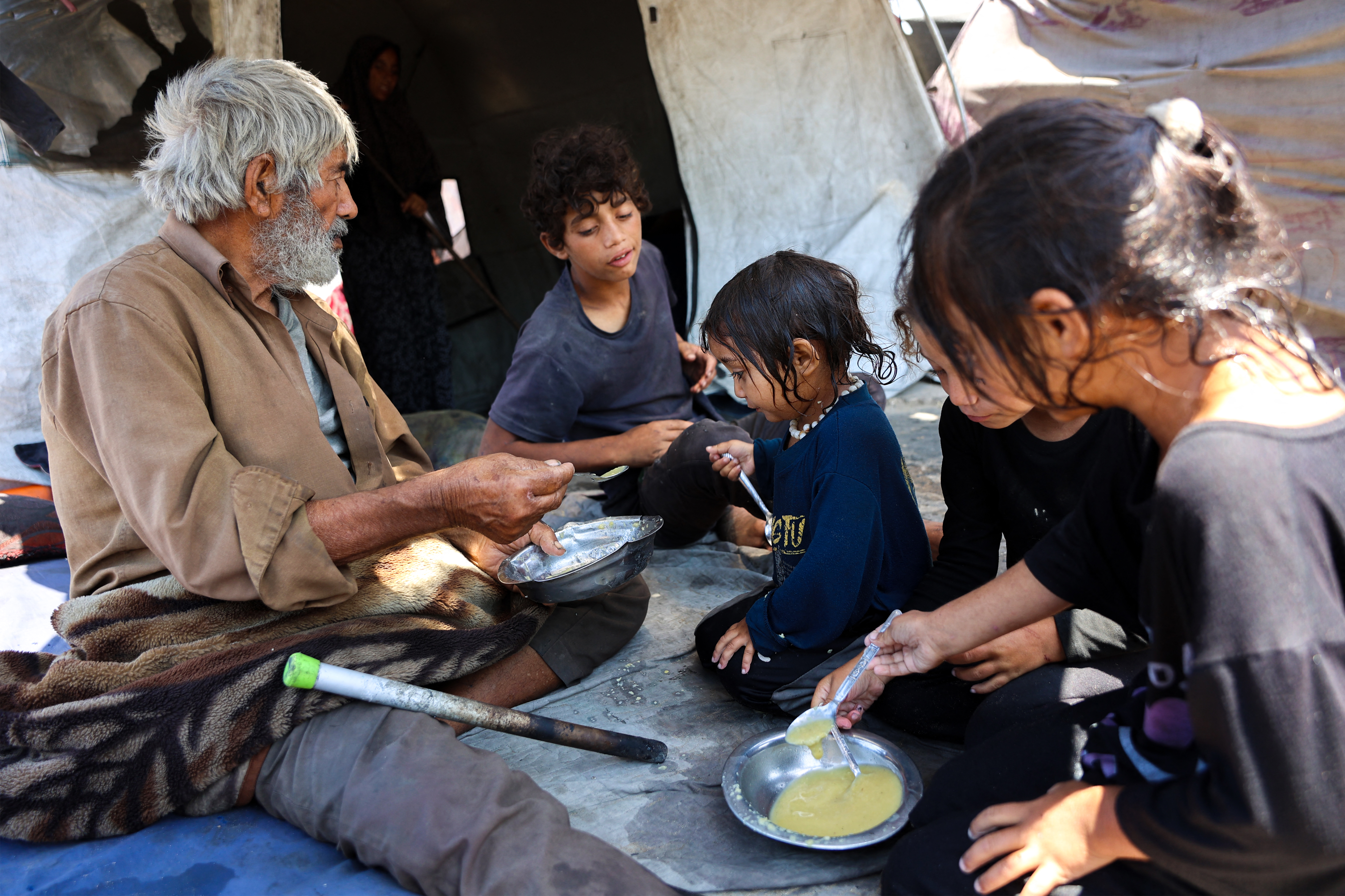A Palestinian family eat lentil soup outside their tent in the Daraj neighbourhood in Gaza City
