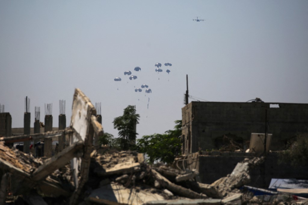 A military plane parachutes aid packages in the Nuseirat area in the central Gaza Strip during an airdrop above the Israel-besieged Palestinian territory on August 6, 2025. (Photo by Eyad BABA / AFP)