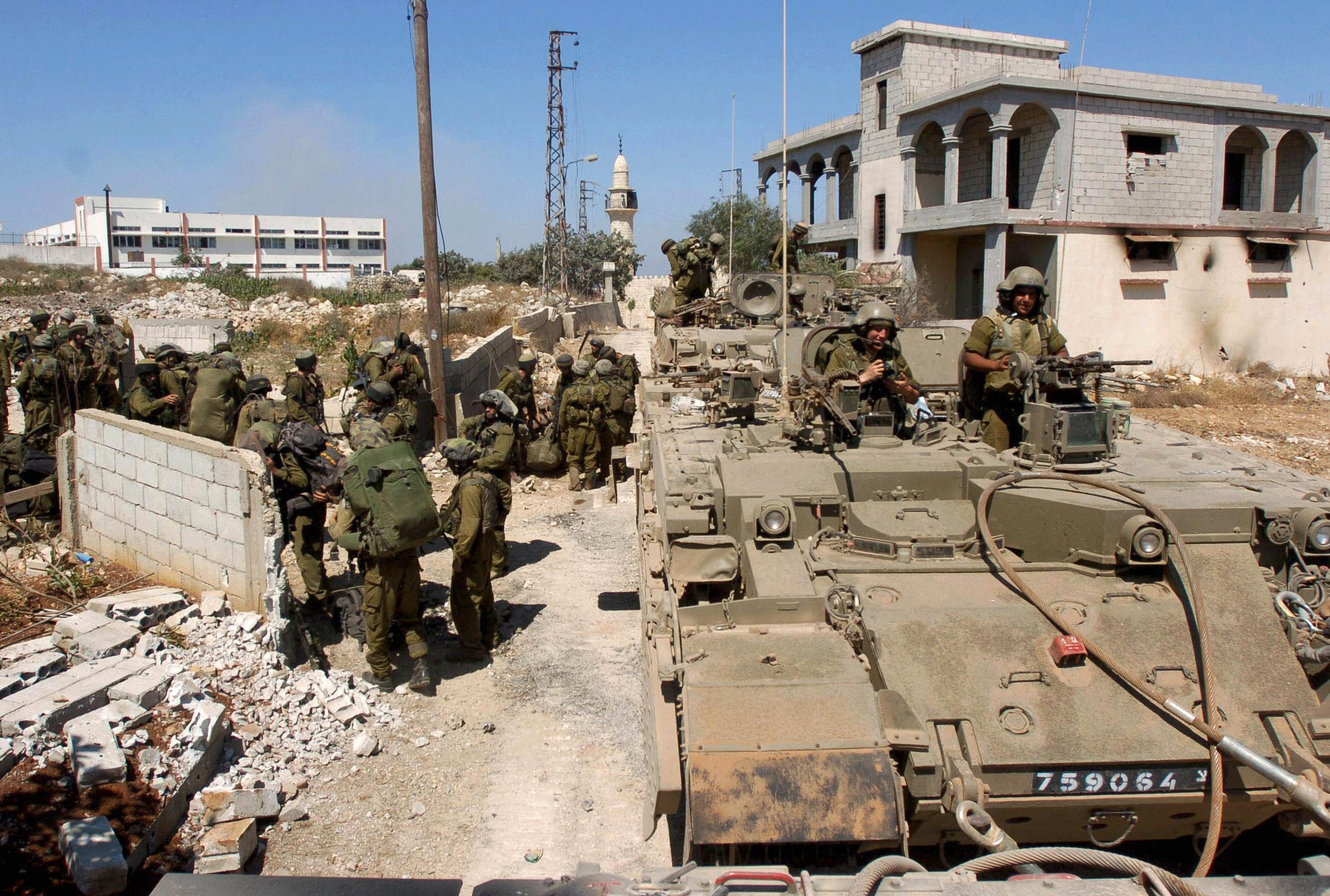 In this photo released by the Israeli army, Israeli soldiers stand next to a tank in the southern Lebanese village of Marun al-Ras