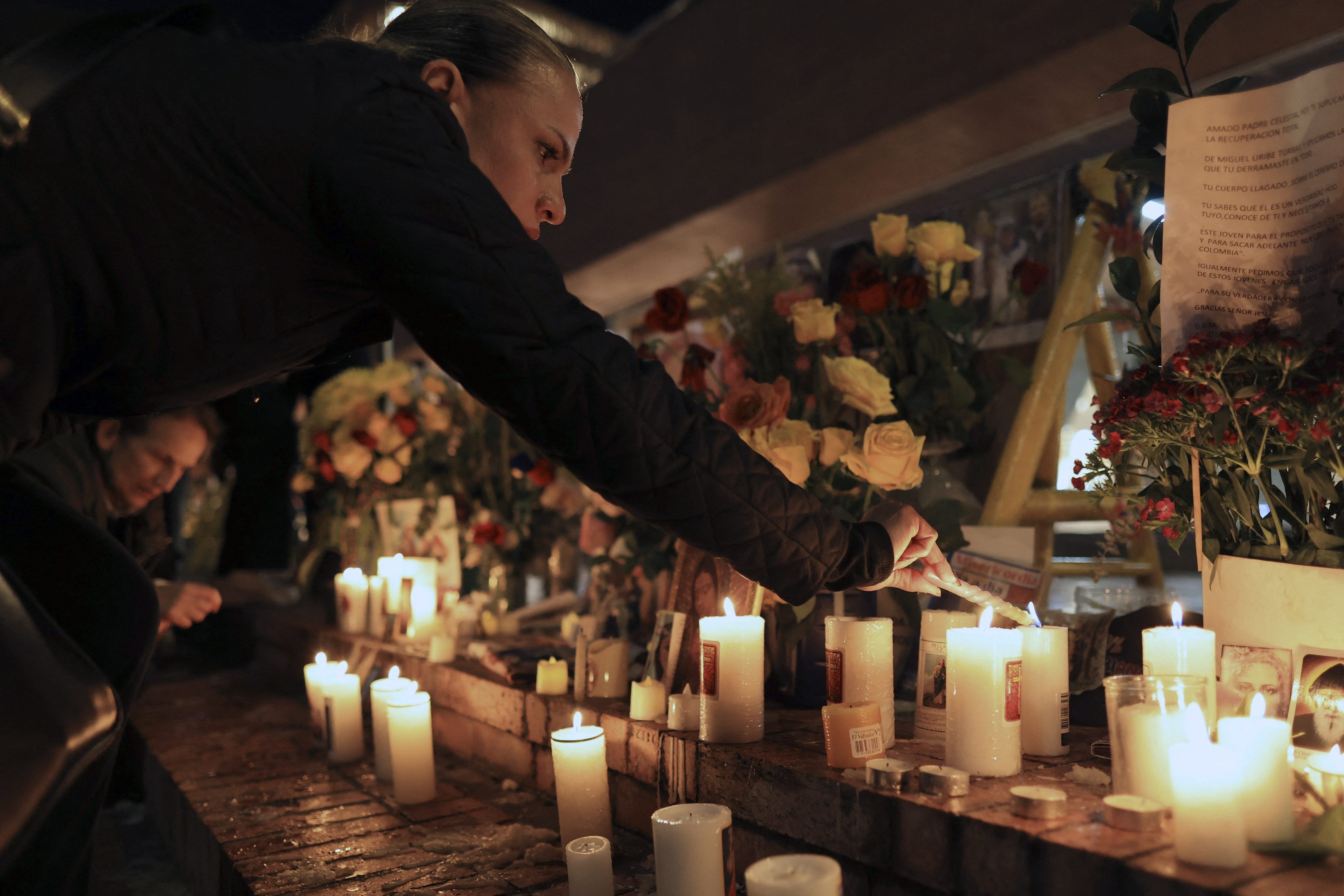 A woman lights a candle during a vigil outside the Fundacion Santa Fe clinic