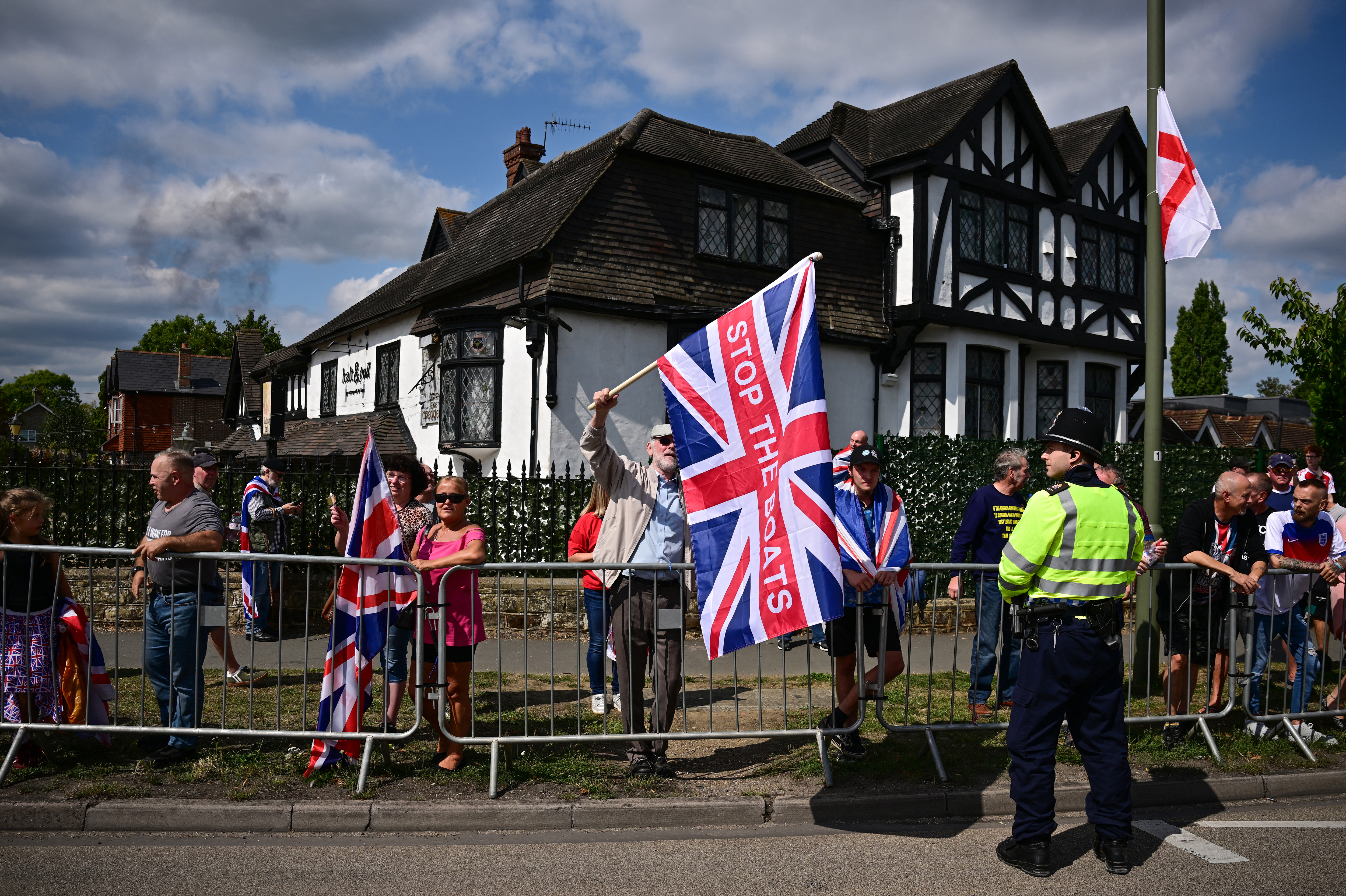 A protestor holds a Union Flag reading 'Stop The Boats' during an anti-immigration protest outside the Sheraton Four Points hotel, believed to be housing asylum seekers, in Horley, south of London, on August 23, 2025.