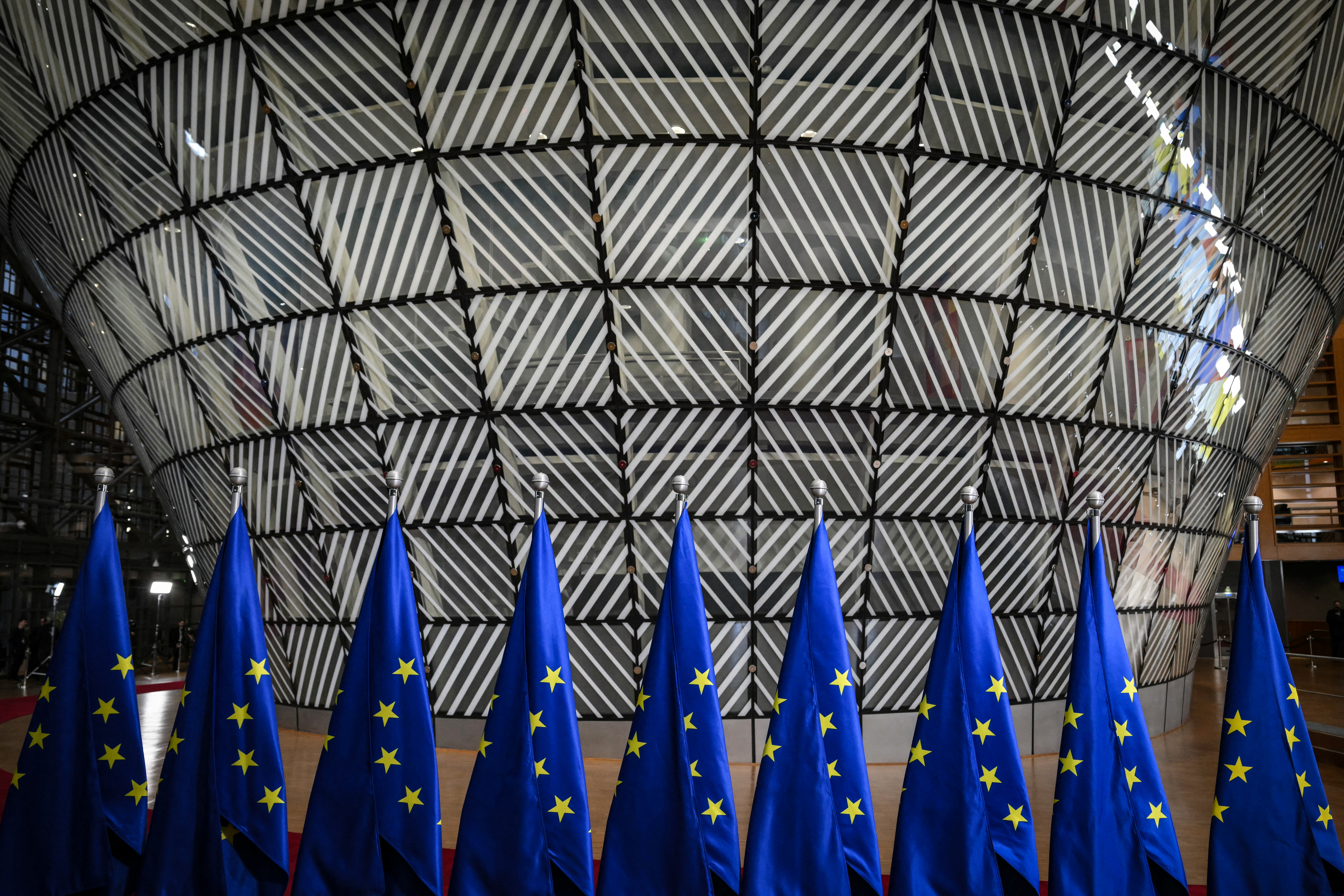 A photo shows European Union flags in the Europa Building before the EU-Western Balkans summit at the European Council in Brussels on December 18, 2024. (Photo by NICOLAS TUCAT / AFP)
