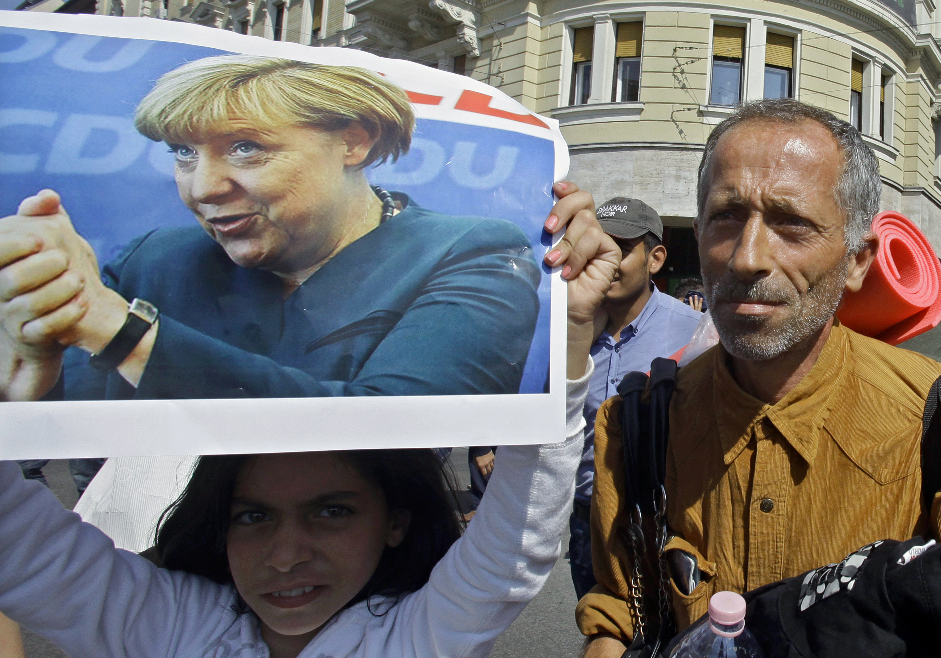 a migrant girl holds a poster of then German Chancellor Angela Merkel