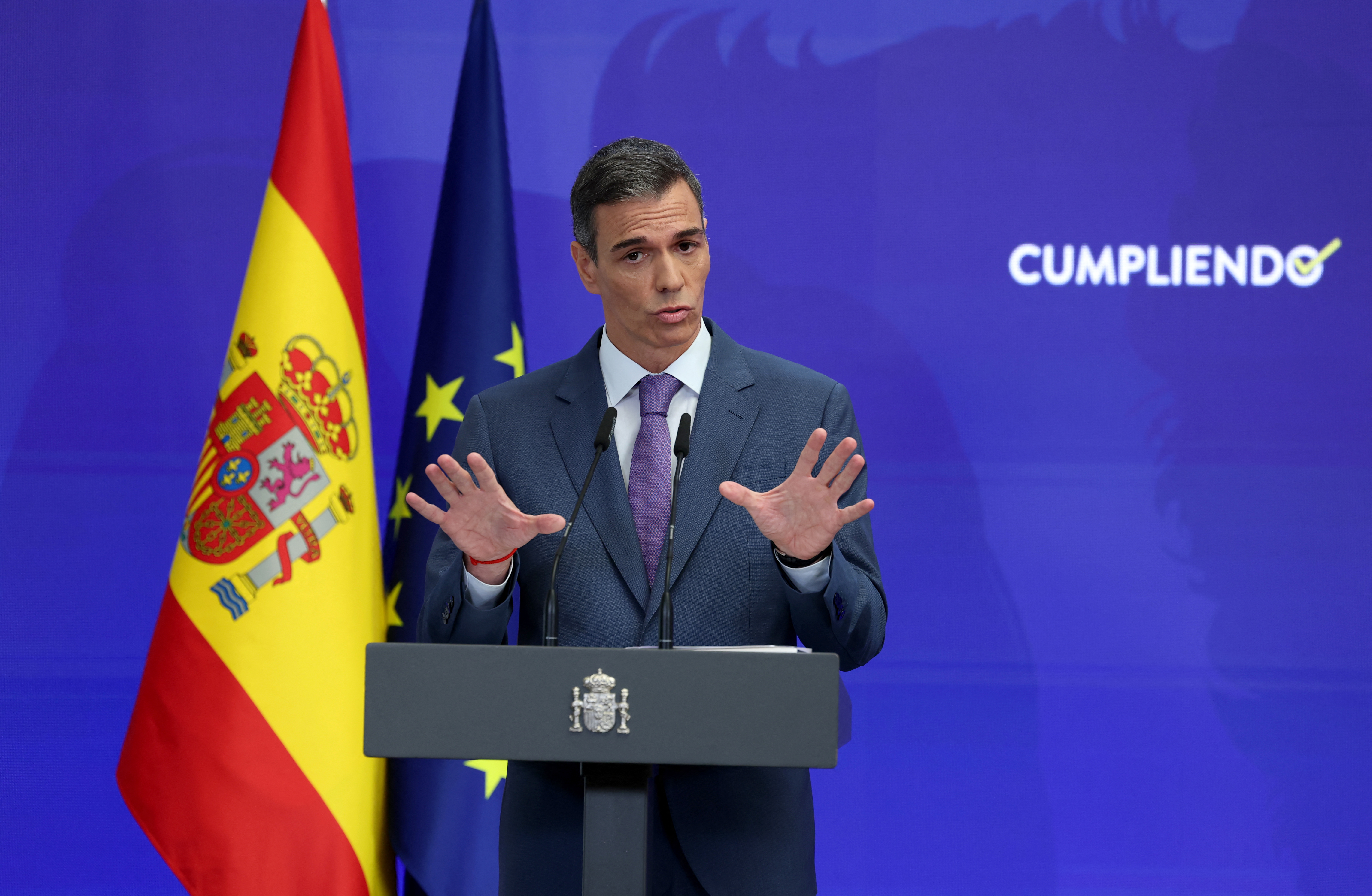Spain's Prime Minister Pedro Sanchez speaks next to the word reading 'accomplishing' during a biannual press conference at La Moncloa Palace in Madrid