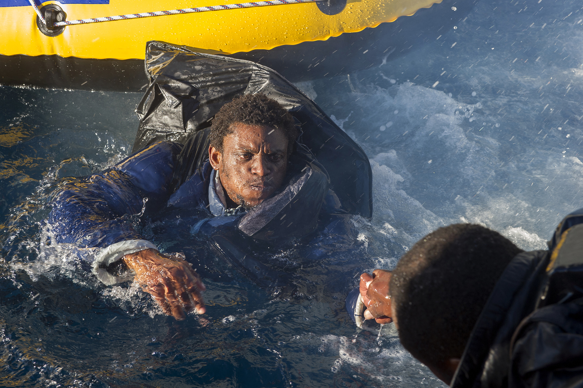 A would-be immigrant is helped to get on board a Spanish emergency services (Salvamento Maritimo) boat off the Spanish coast, on December 3, 2012.
