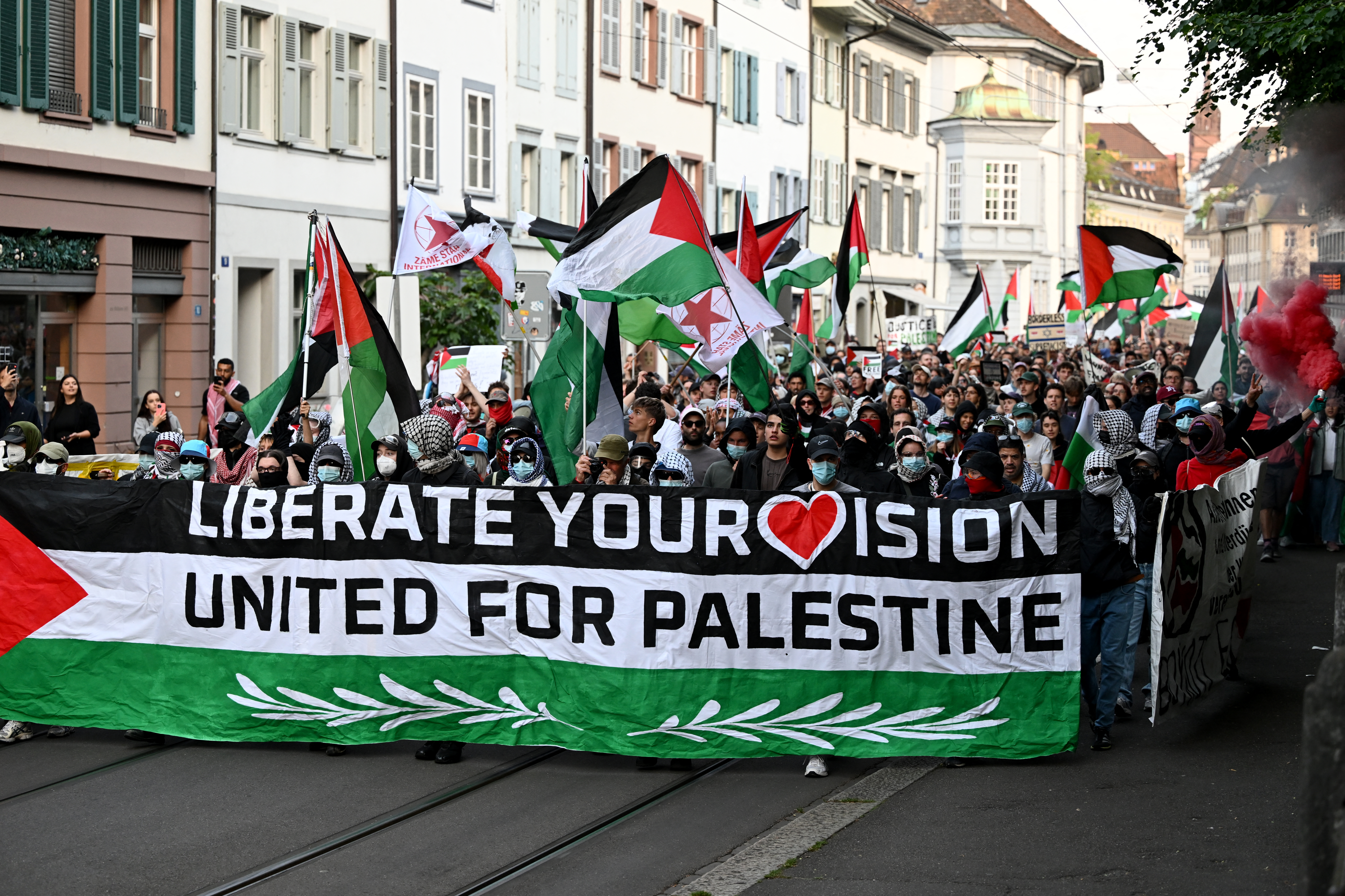 Protestors hold a banner and Palestinian flags during a demonstration against Israel's candidate prior to the grand final of the Eurovision Song Contest 2025