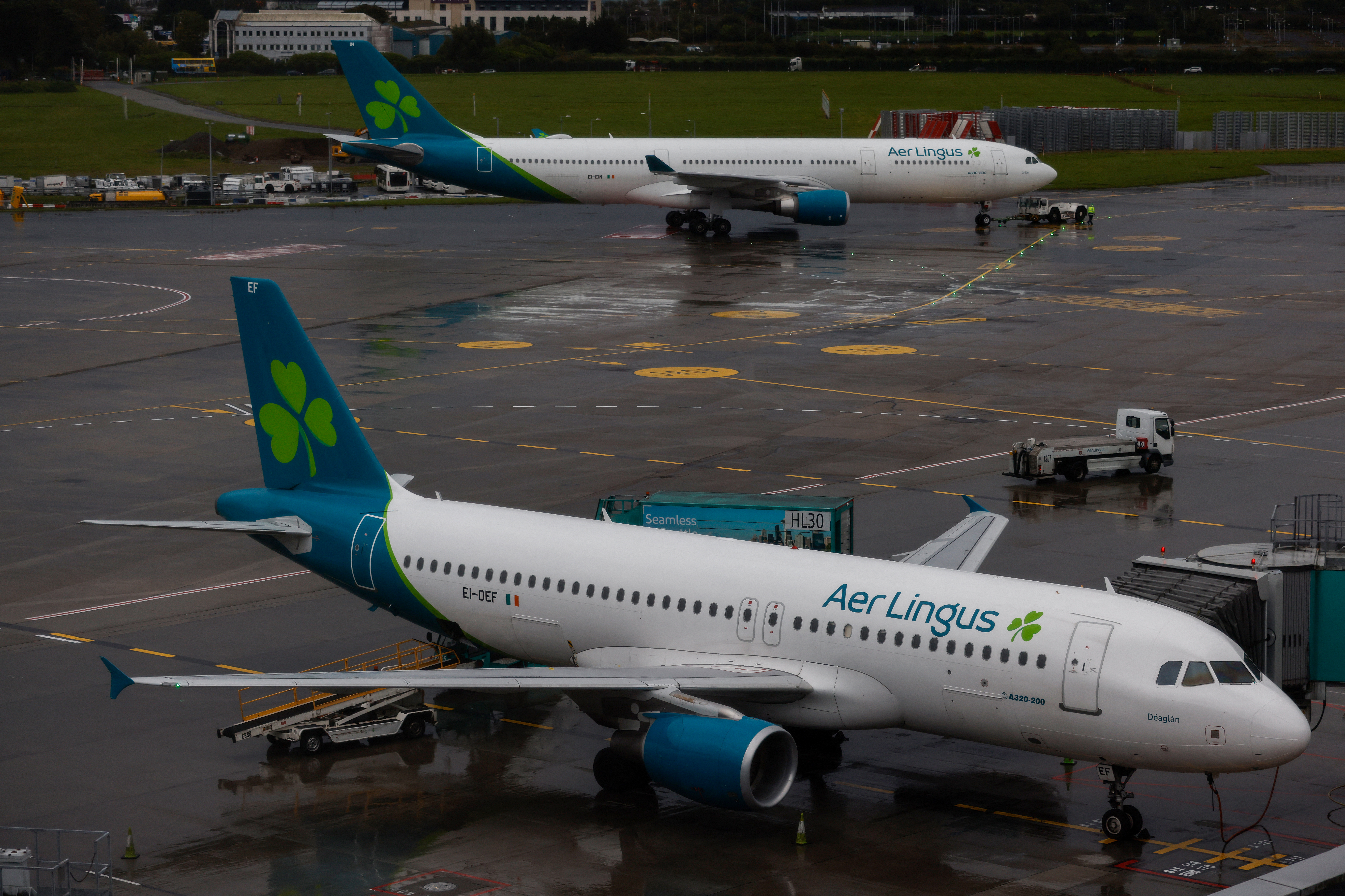 An Aer Lingus passenger jet makes its way to the runway for take off while another is parked at at a Gate at Dublin Airport in Ireland