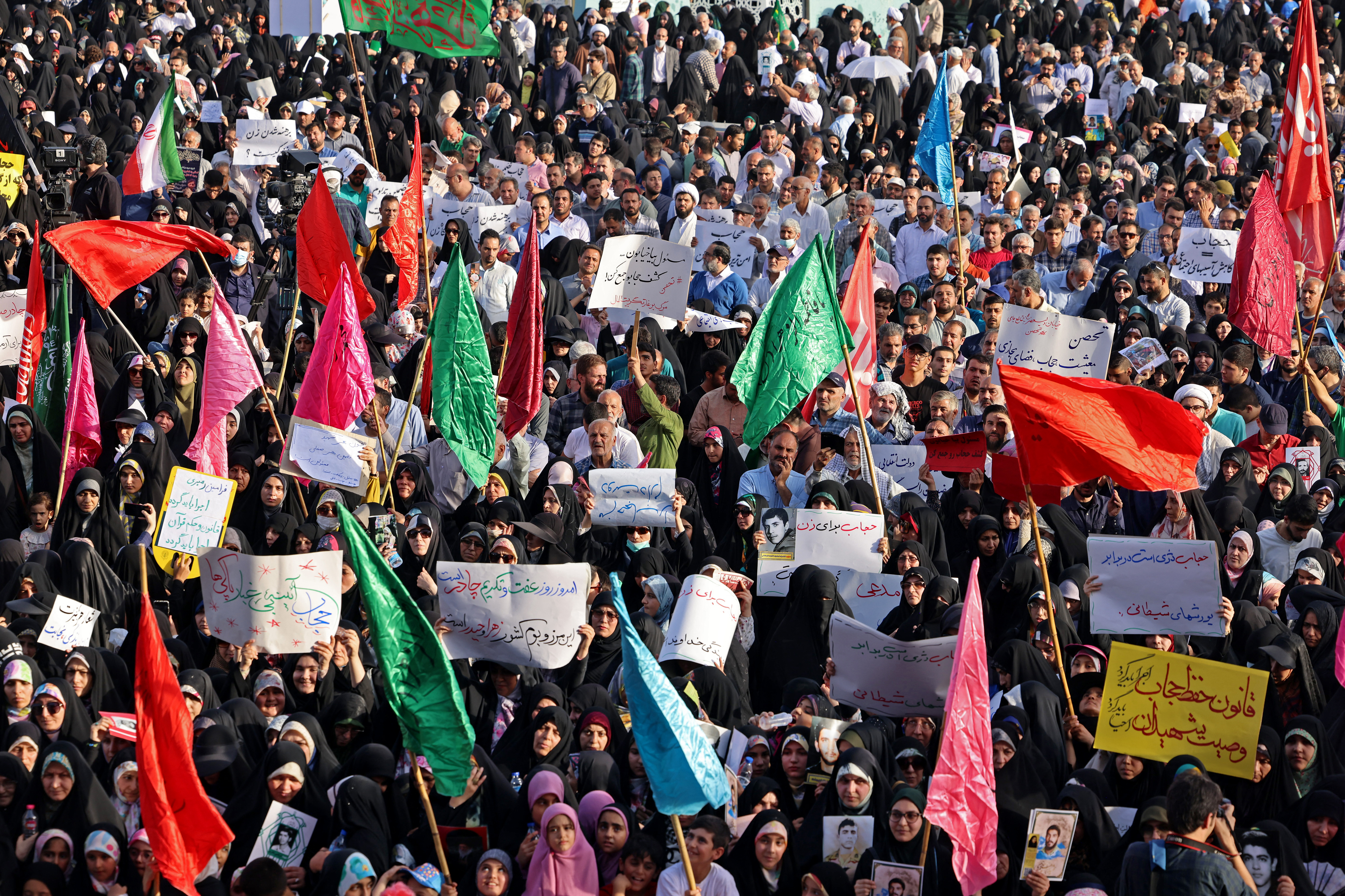 Iranians wave flags during a pro-hijab rally in Tehran on July 12, 2023. (Photo by ATTA KENARE / AFP)