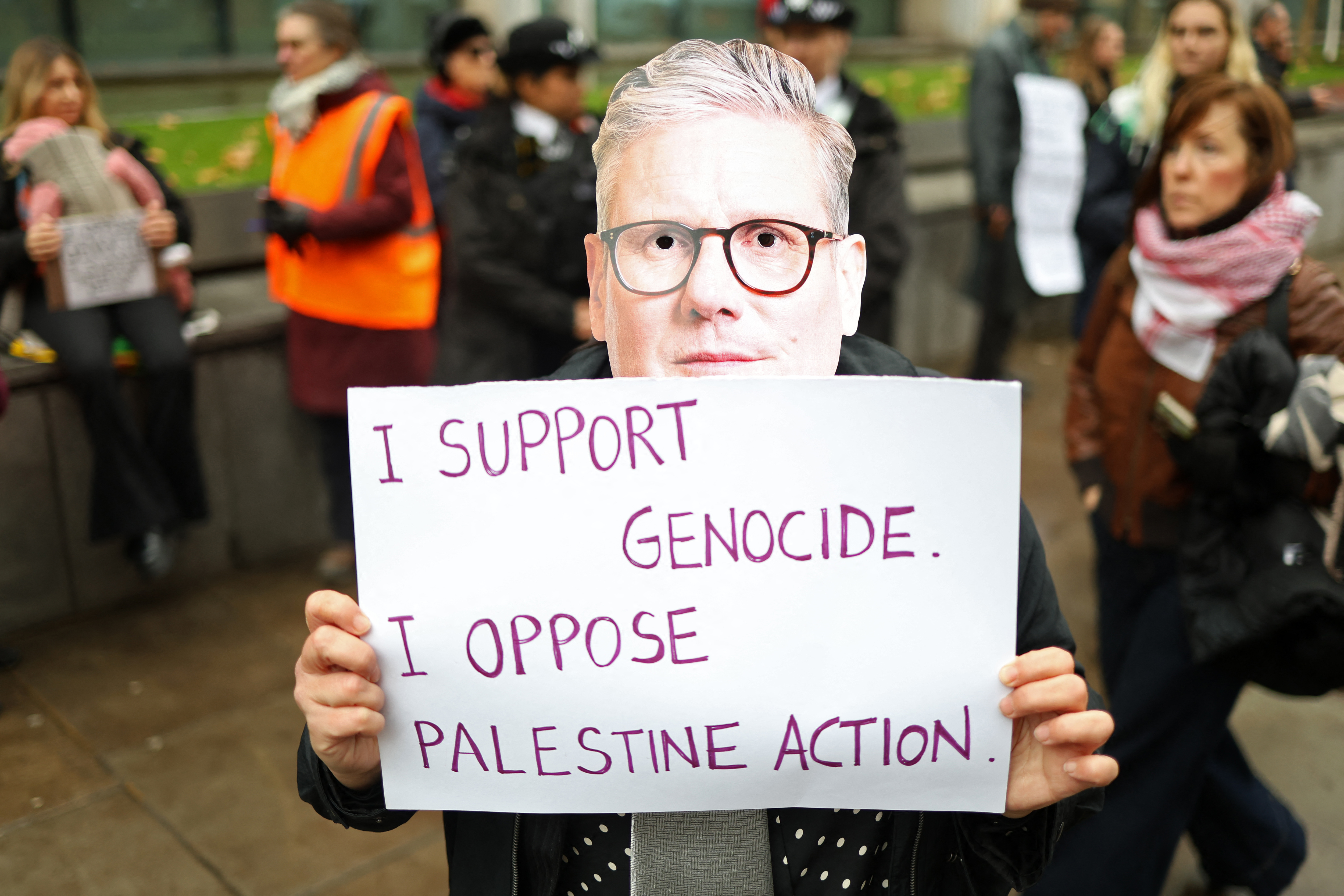 A protester wearing a mask depicting Britain's Prime Minister Keir Starmer