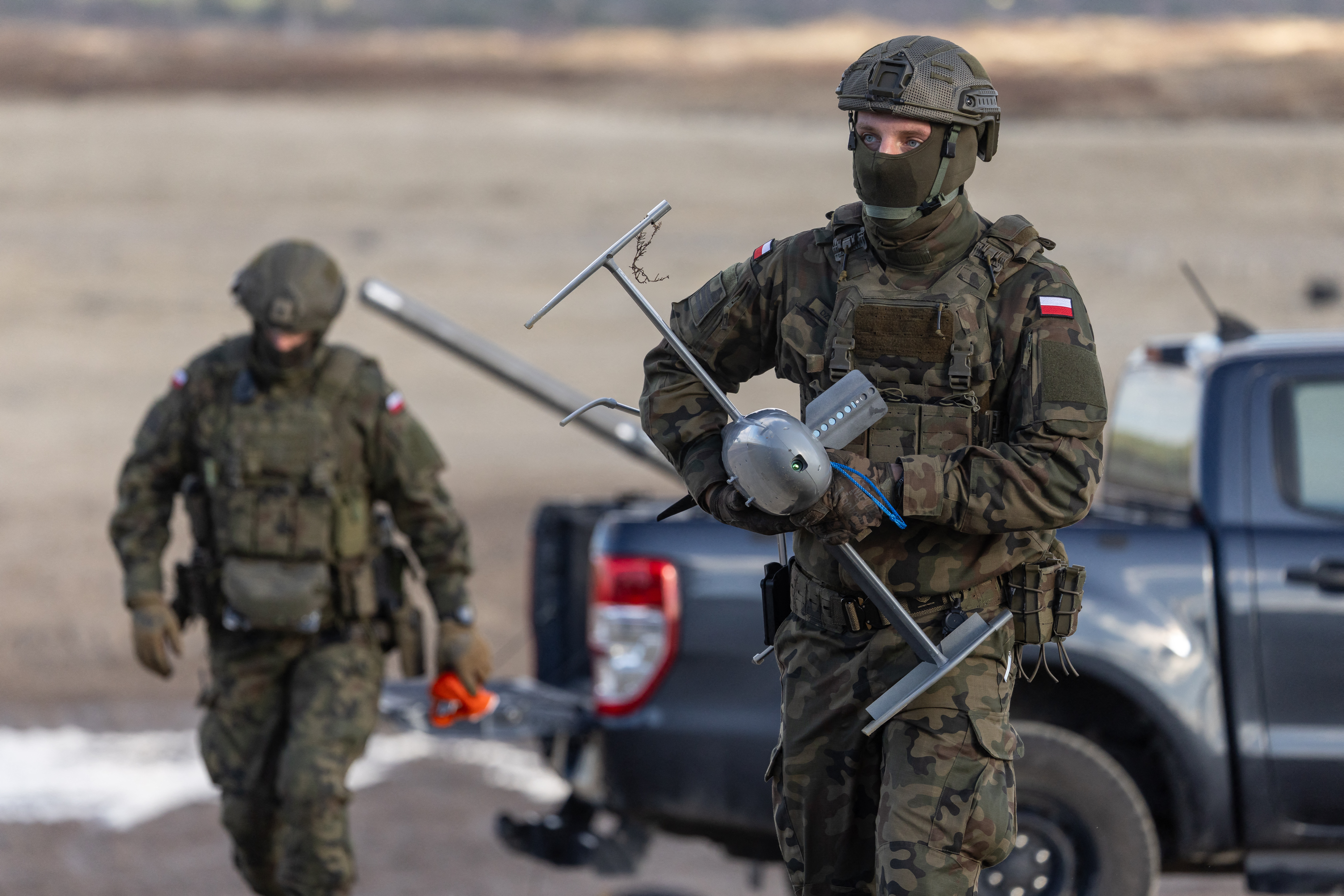 A Polish soldier carries an interception drone of the American MEROPS counter drone system during tests at the Nowa Deba military training ground, south-eastern Poland, on November 18, 2025. (Photo by Wojtek RADWANSKI / AFP)