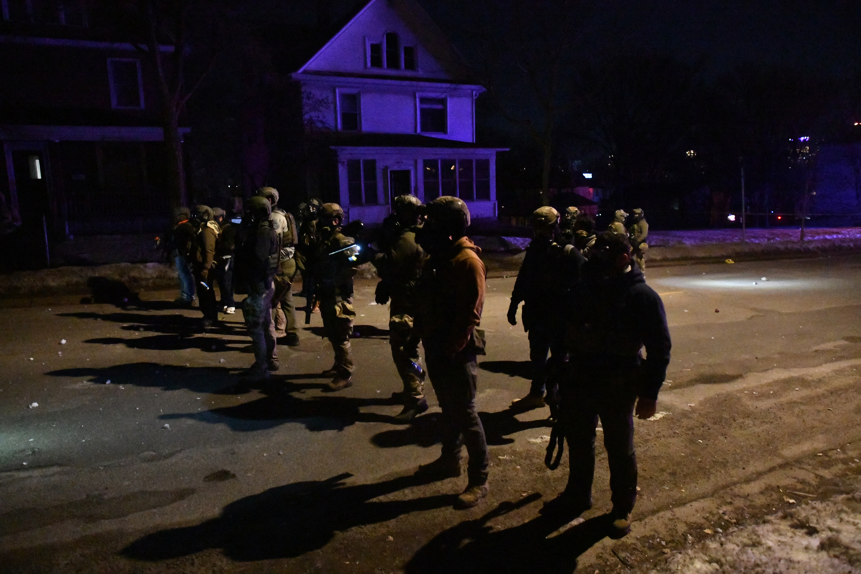 Federal law enforcement agents and police officers in riot gear aim smoke crowd-control devices to disperse protesters following the shooting of a Venezuelan man by a Immigration and Customs Enforcement (ICE) agent