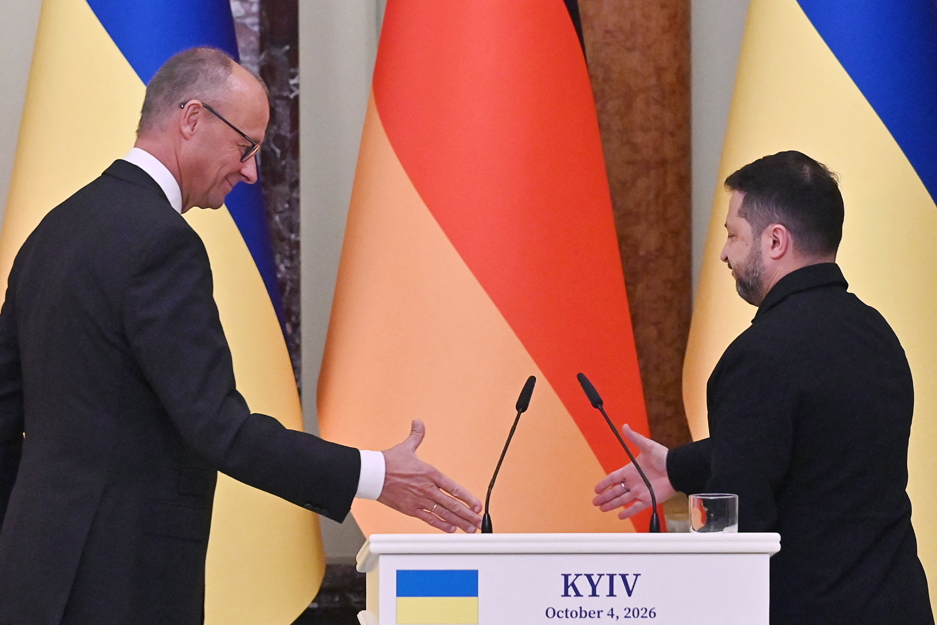 Ukraine's President Volodymyr Zelensky (R) and Germany's Chancellor Friedrich Merz shake hands as they hold a press conference in Mariinsky Palace following talks in Kyiv on October 4, 2026, amid the Russian invasion of Ukraine